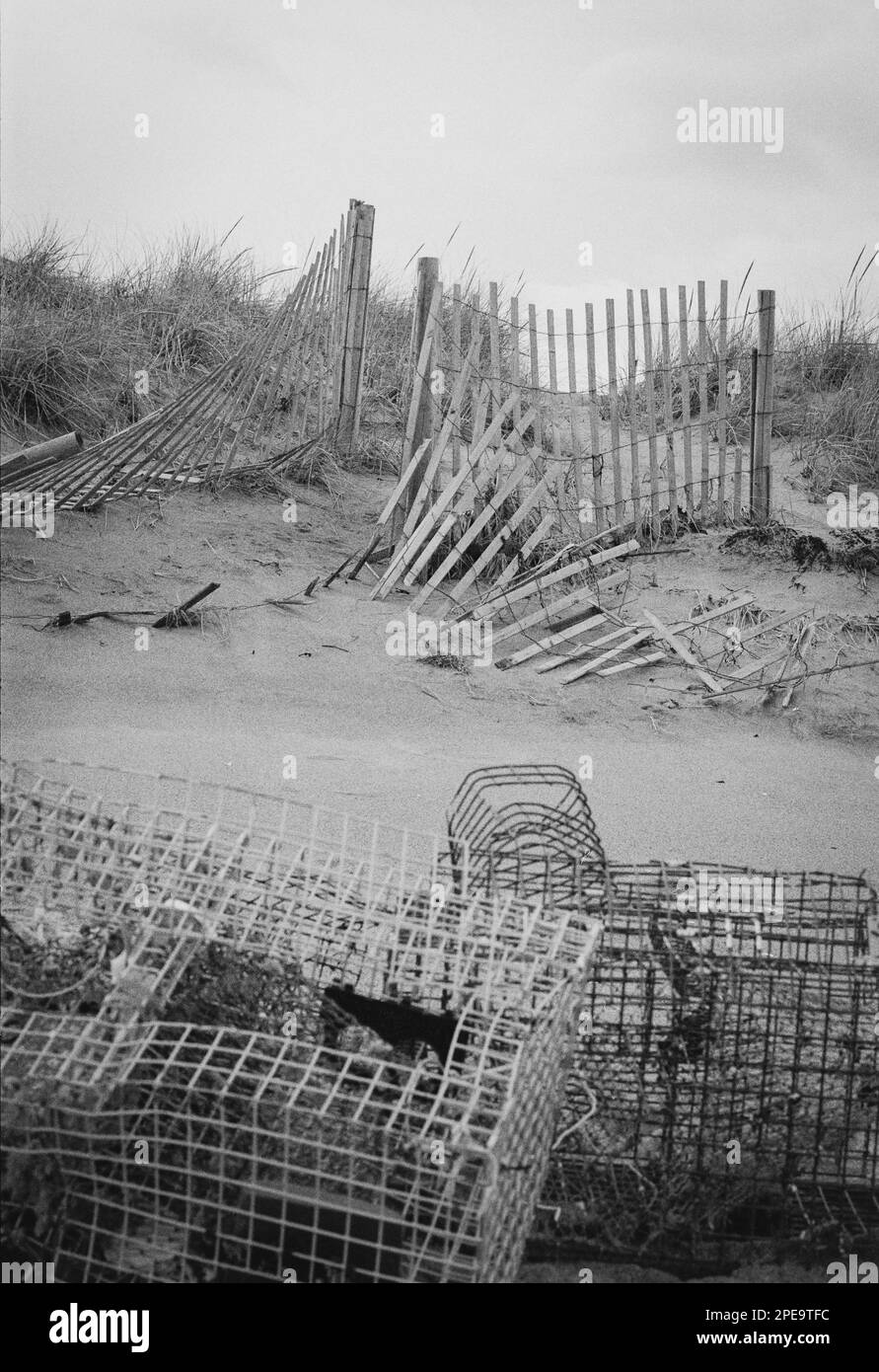 Abandoned old lobster traps wound together with trash in the sand at Salisbury Beach