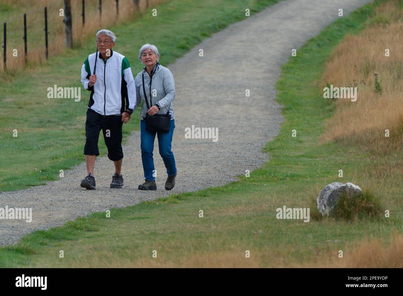 Asian couple hiking outdoors and holding hands on a New Zealand adventure, Castle Hill, South Island, New Zealand. Stock Photo