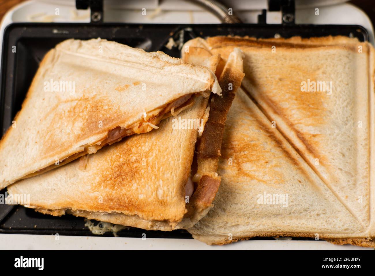 https://c8.alamy.com/comp/2PEBHXY/freshly-made-toasted-sandwiches-in-a-sandwich-maker-on-a-wooden-background-toasted-triangular-sandwiches-with-cheese-2PEBHXY.jpg