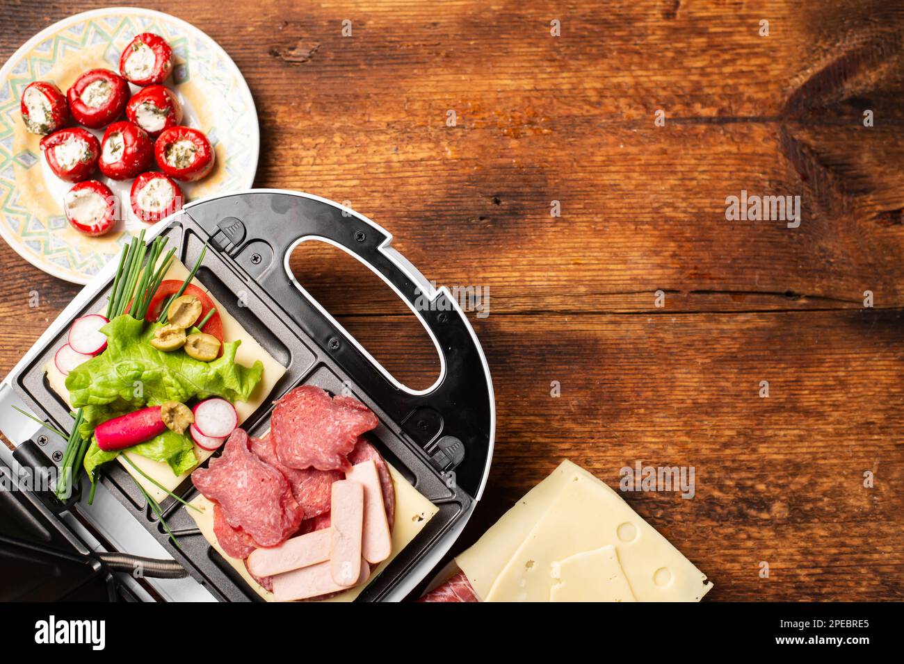 Different types of sandwiches in a sandwich maker on a wooden