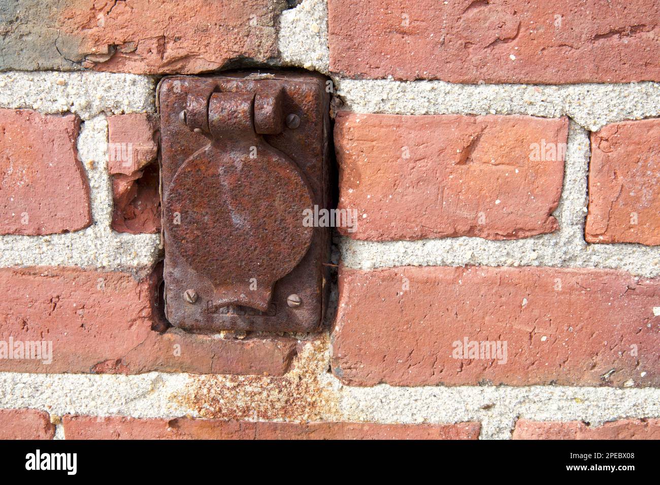 Rusted, metal outlet on old, brick wall of red color. Textured