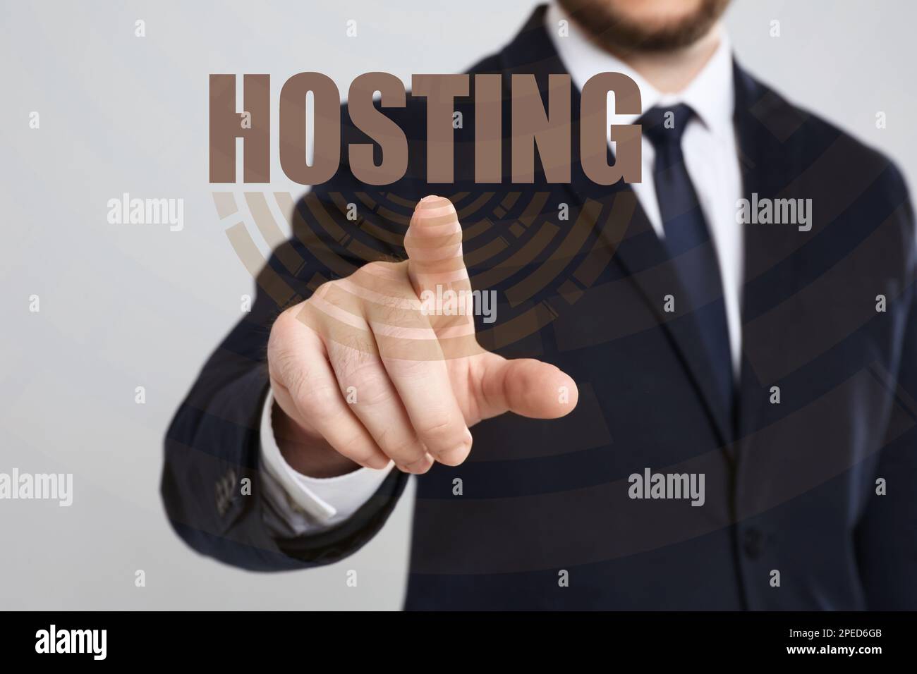 Businessman pointing at word HOSTING on virtual screen against light background, focus on hand Stock Photo