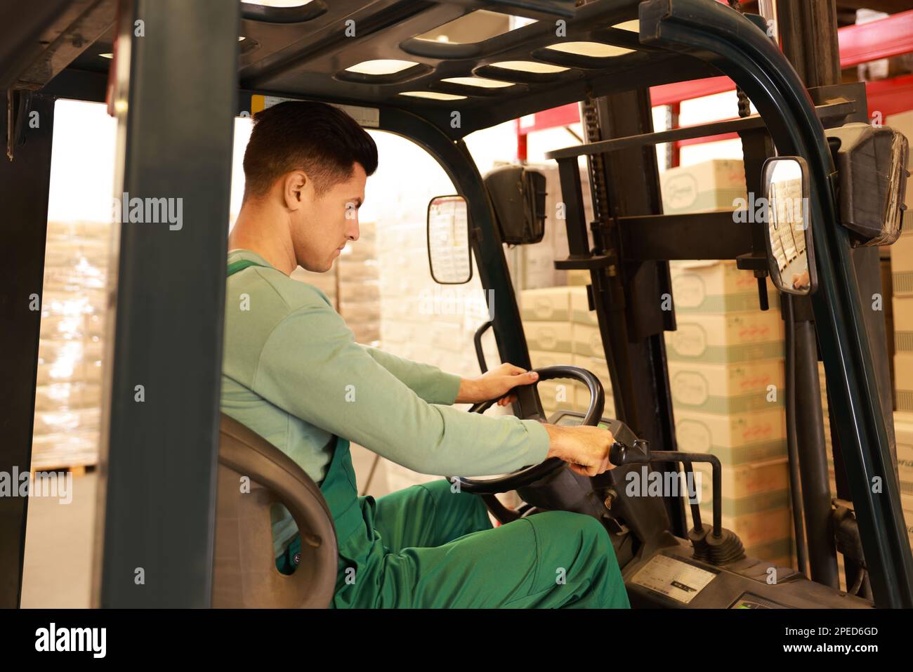 Worker sorting cardboard boxes with forklift truck in warehouse ...