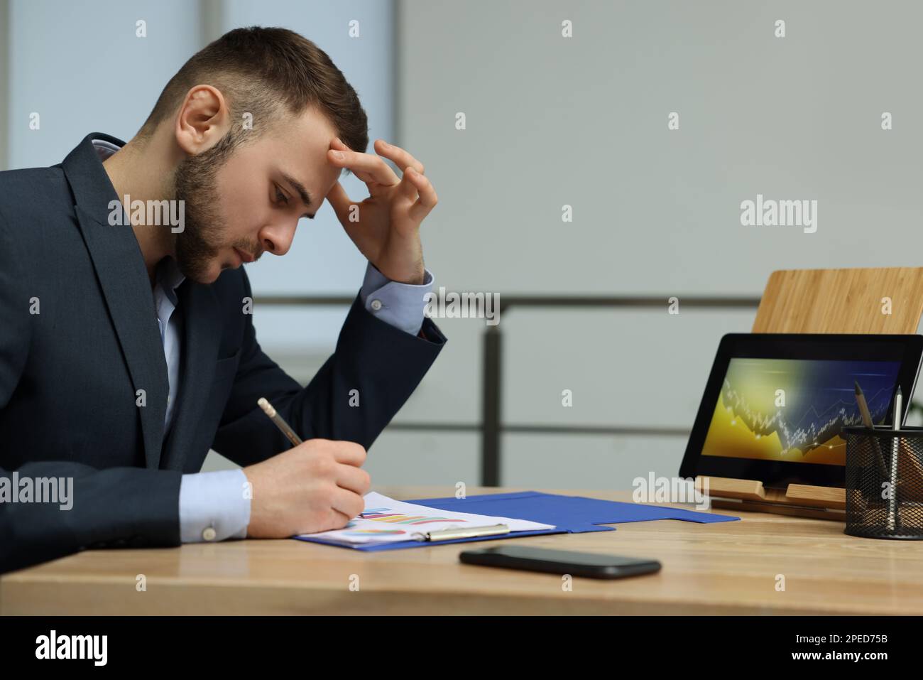 Forex trader working with tablet and documents at table in office Stock Photo