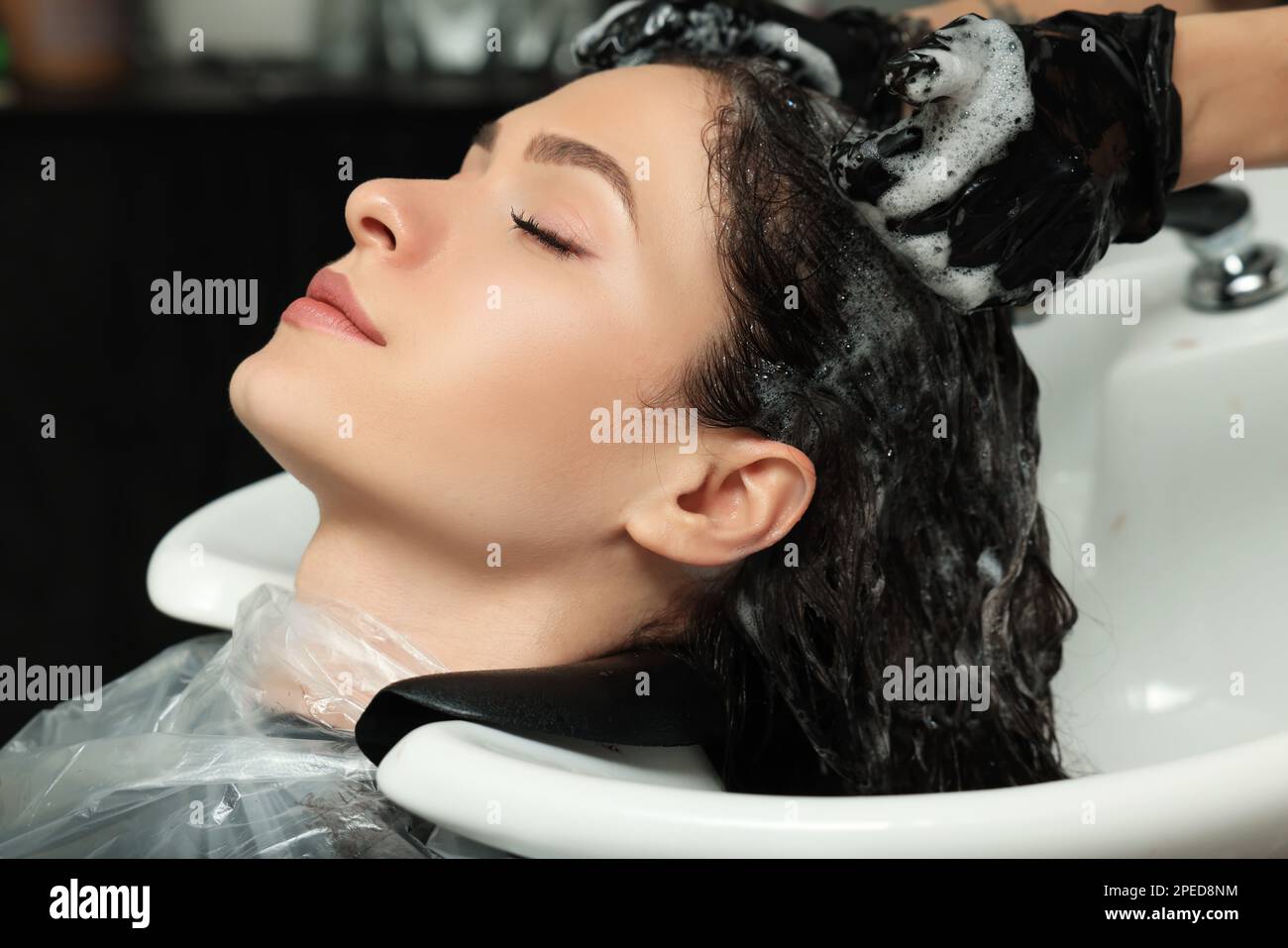 Hairdresser rinsing out dye from woman's hair in beauty salon Stock