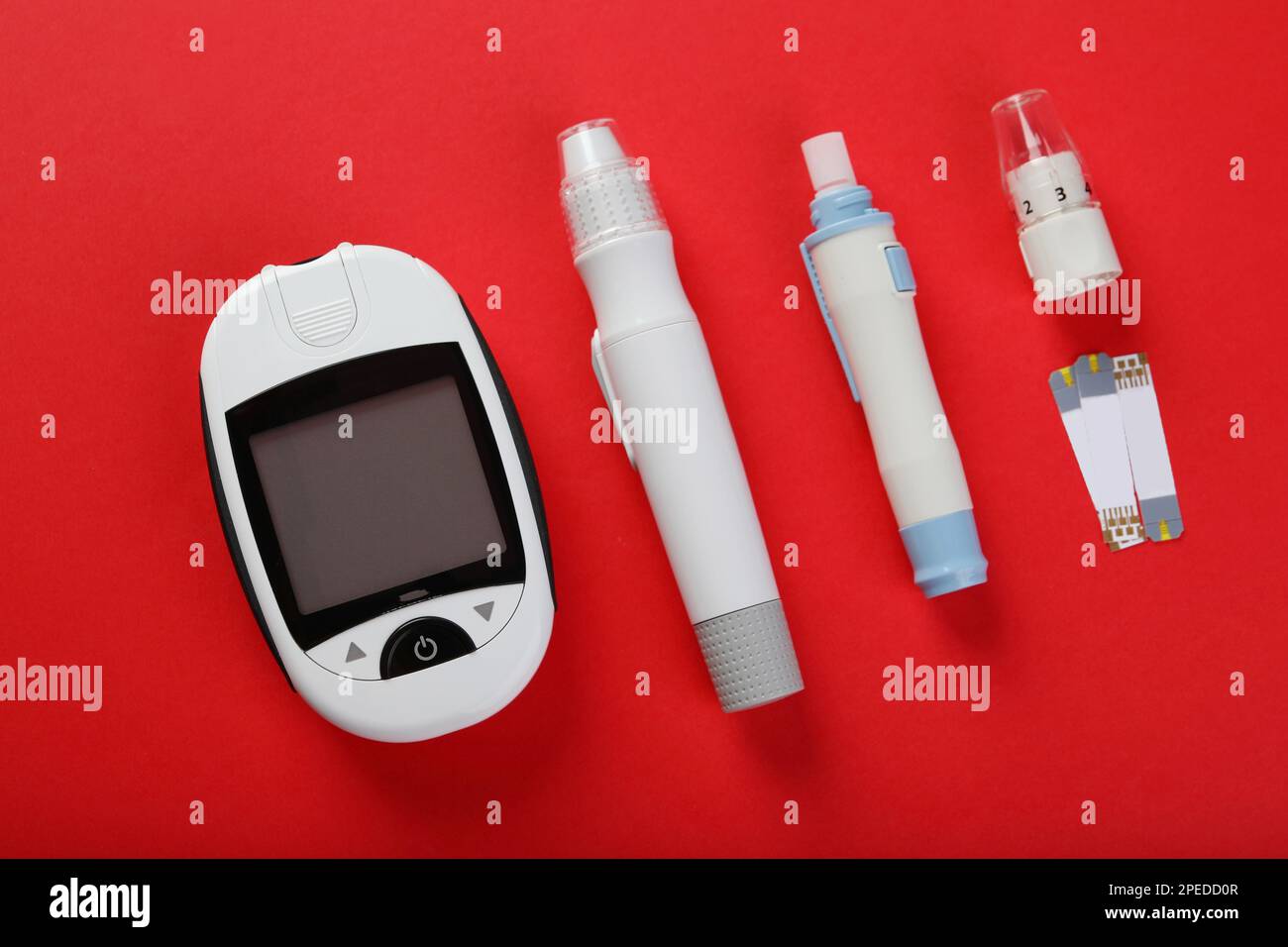 Digital lancet pens and test strips on red background, flat