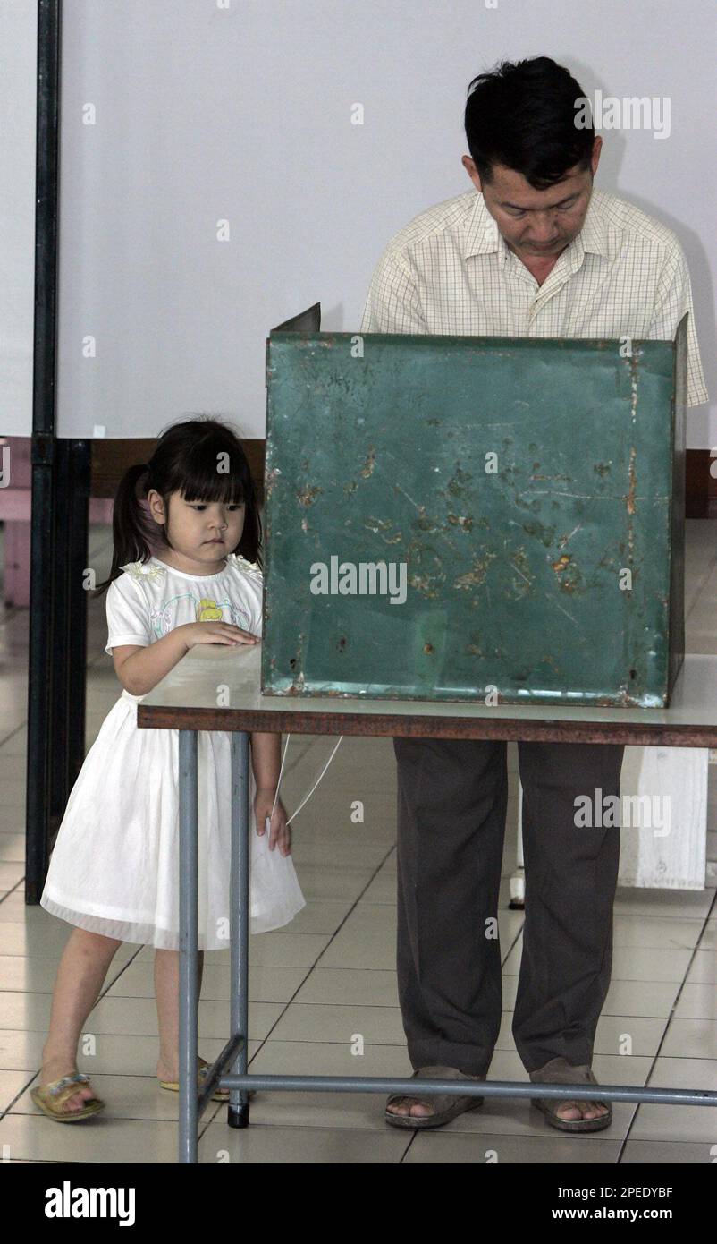 An unidentified Thai man marks his ballot as his daughter looks on Sunday,  Feb. 6, 2005, in Bangkok, Thailand. The state Election Commission conceded  over the weekend that the campaign had been