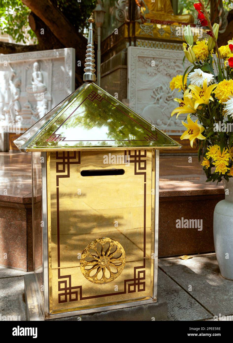 Big golden donation box with a samsara symbol on it at a Buddhist temple.  Large gold collection box for Buddhist shrine support Stock Photo