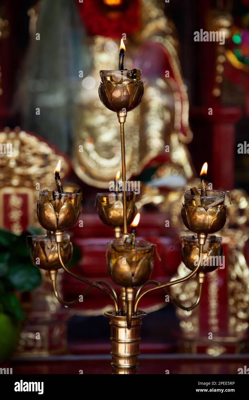 Elegant bronze oil lamp in a form of candelabrum in a Chinese temple. Beautiful golden candle stick with 7 candles burning in a place of worship in As Stock Photo