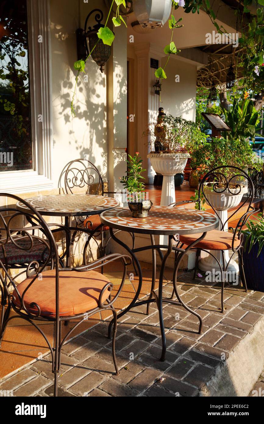 Vintage style sidewalk cafe with beige furniture and lots of plants