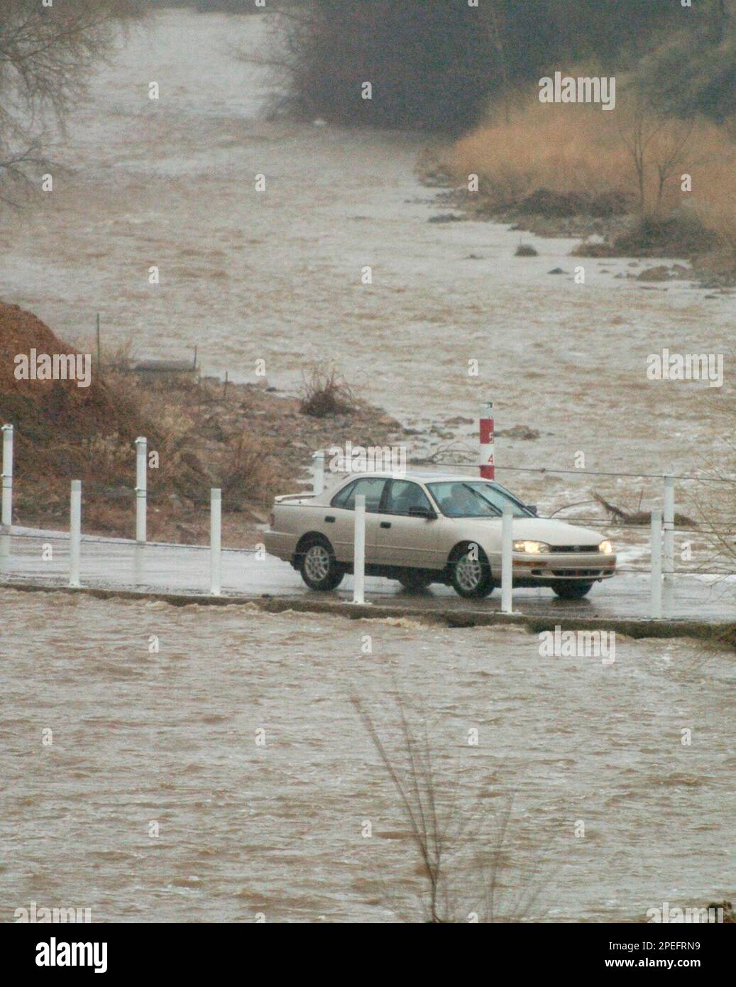 A car crosses the fast running normally dry stream bed on Jack Drive