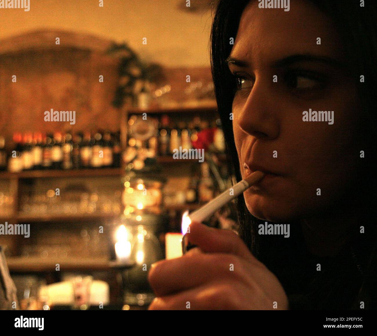 A woman lights a cigarette in a bar in downtown Rome Sunday, Jan.9