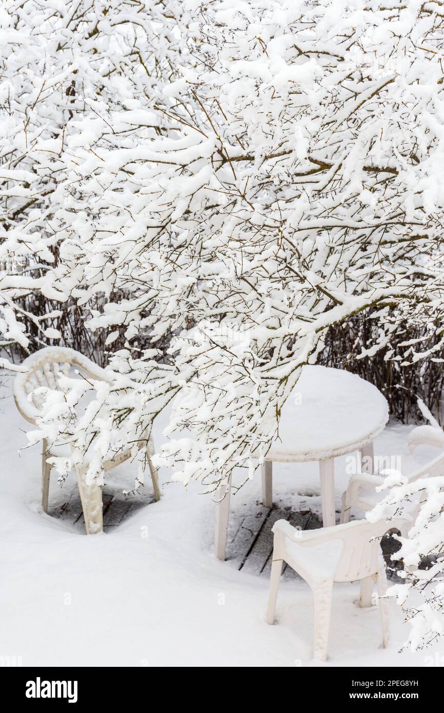 White plastic garden table and chairs in snowy bush landscape in Finland Stock Photo