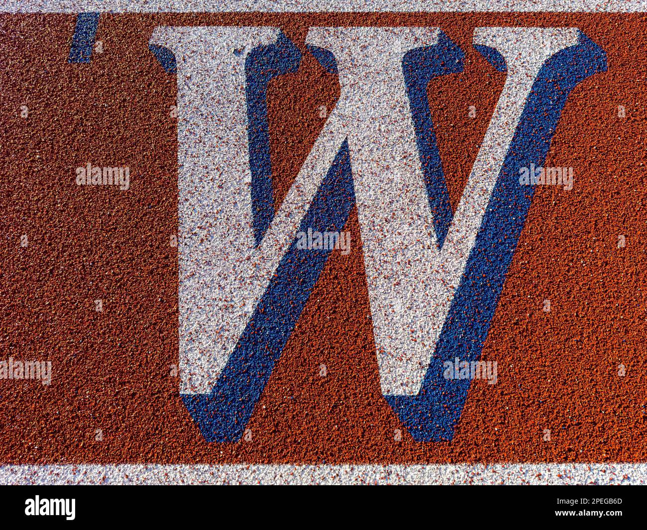 Close up of the letter W on new red running track with white lane lines and other markings. Stock Photo