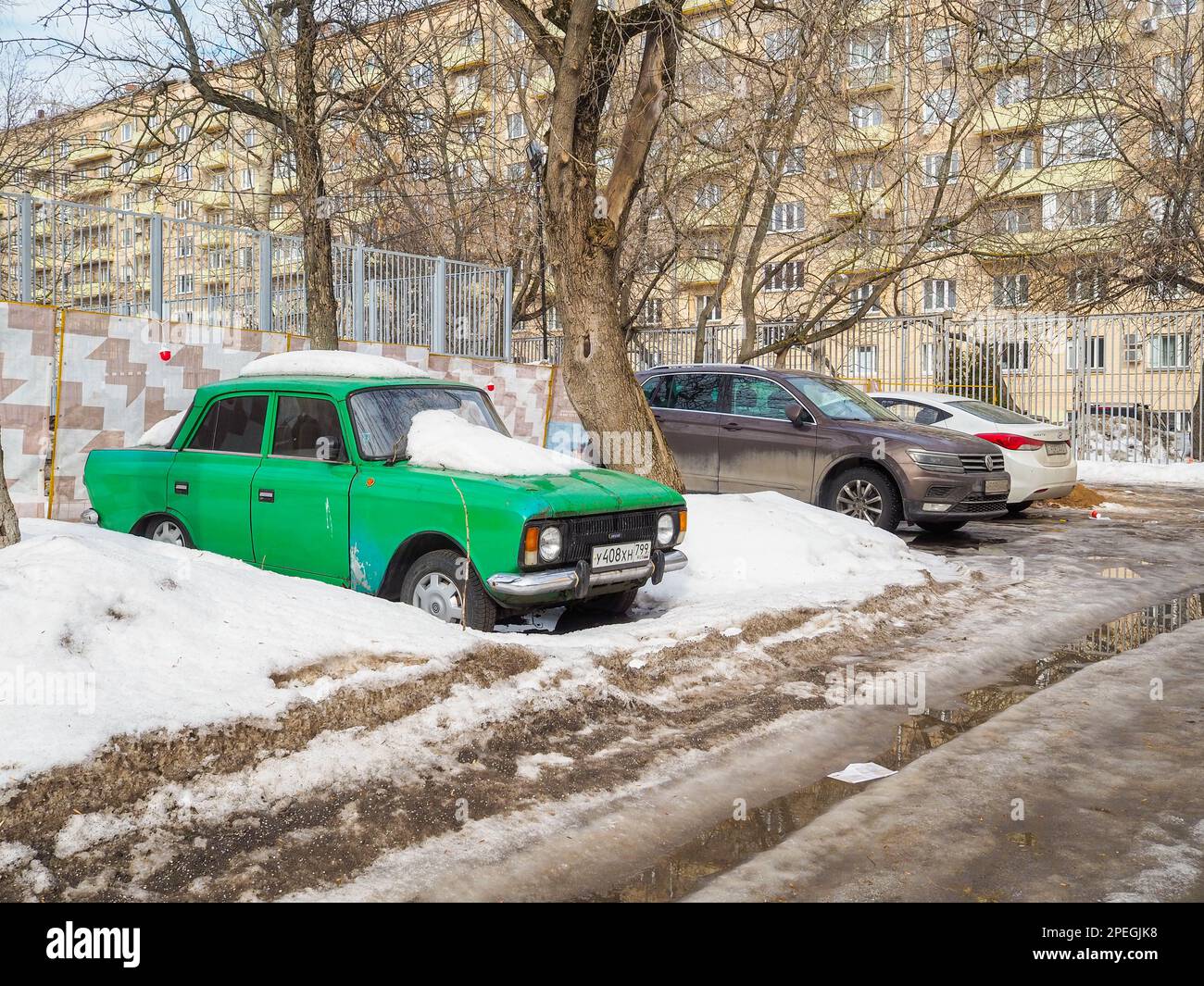Moscow. Russia. March 15, 2023. Old vintage green Soviet car Izh Moskvich is parked in a Moscow courtyard on a spring day among heaps of melting snow. Stock Photo