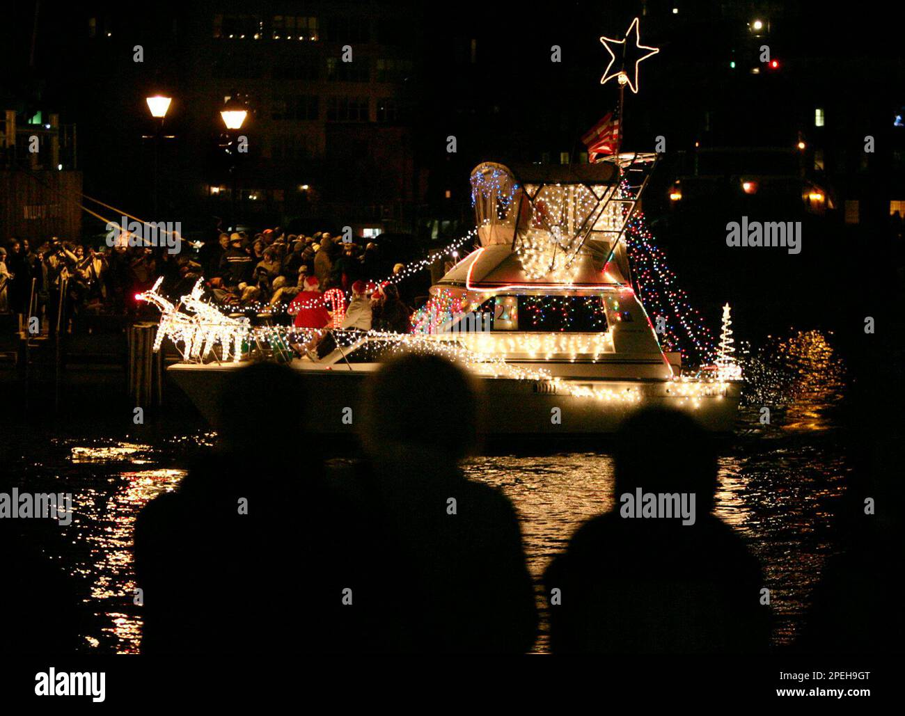 A power boat decorated in Christmas lights floats past spectators around Fells Point in