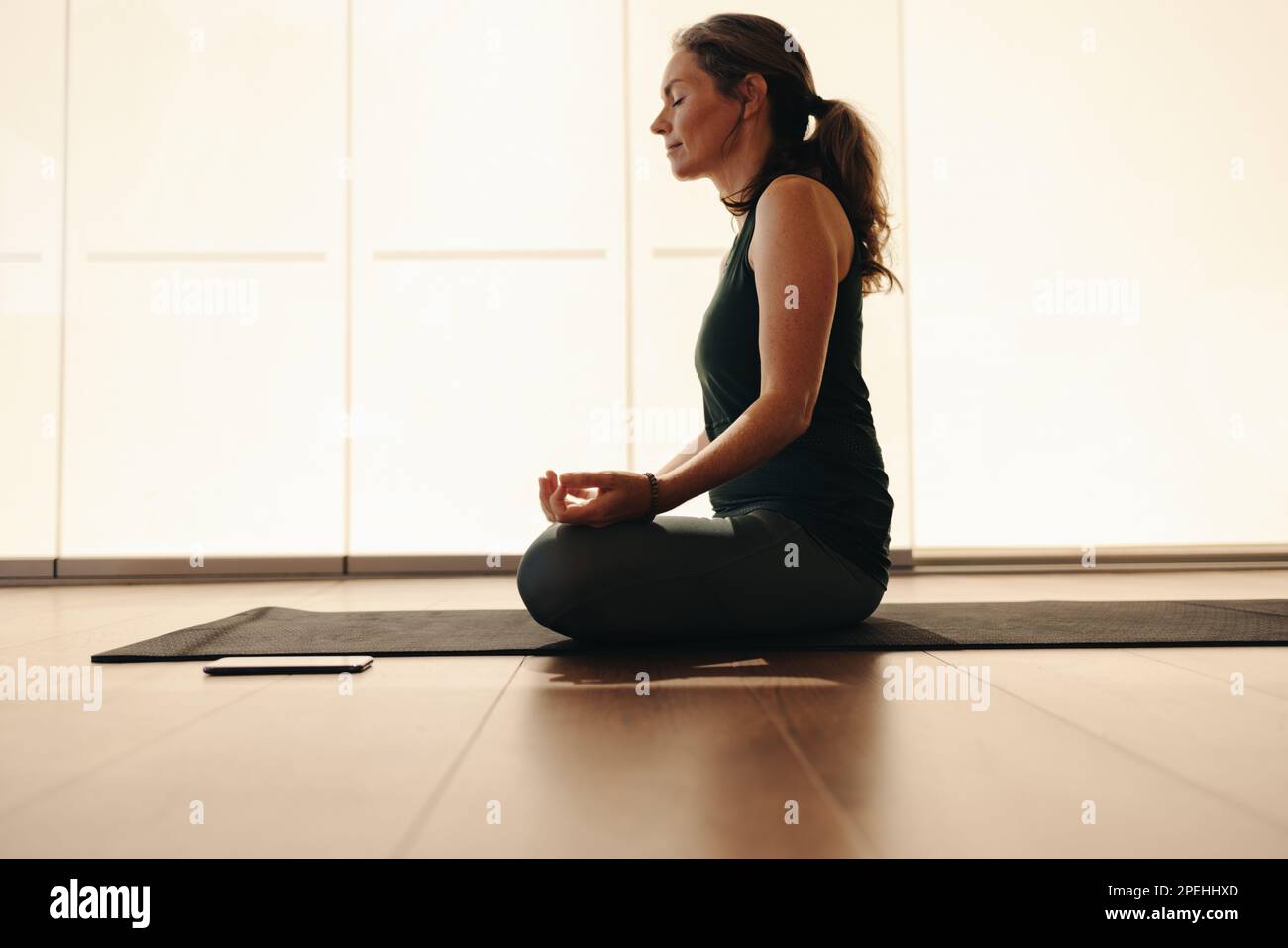 Mature woman meditating while sitting in easy pose. Senior woman doing a breathing exercise during a session of hatha yoga. Woman taking care of her a Stock Photo