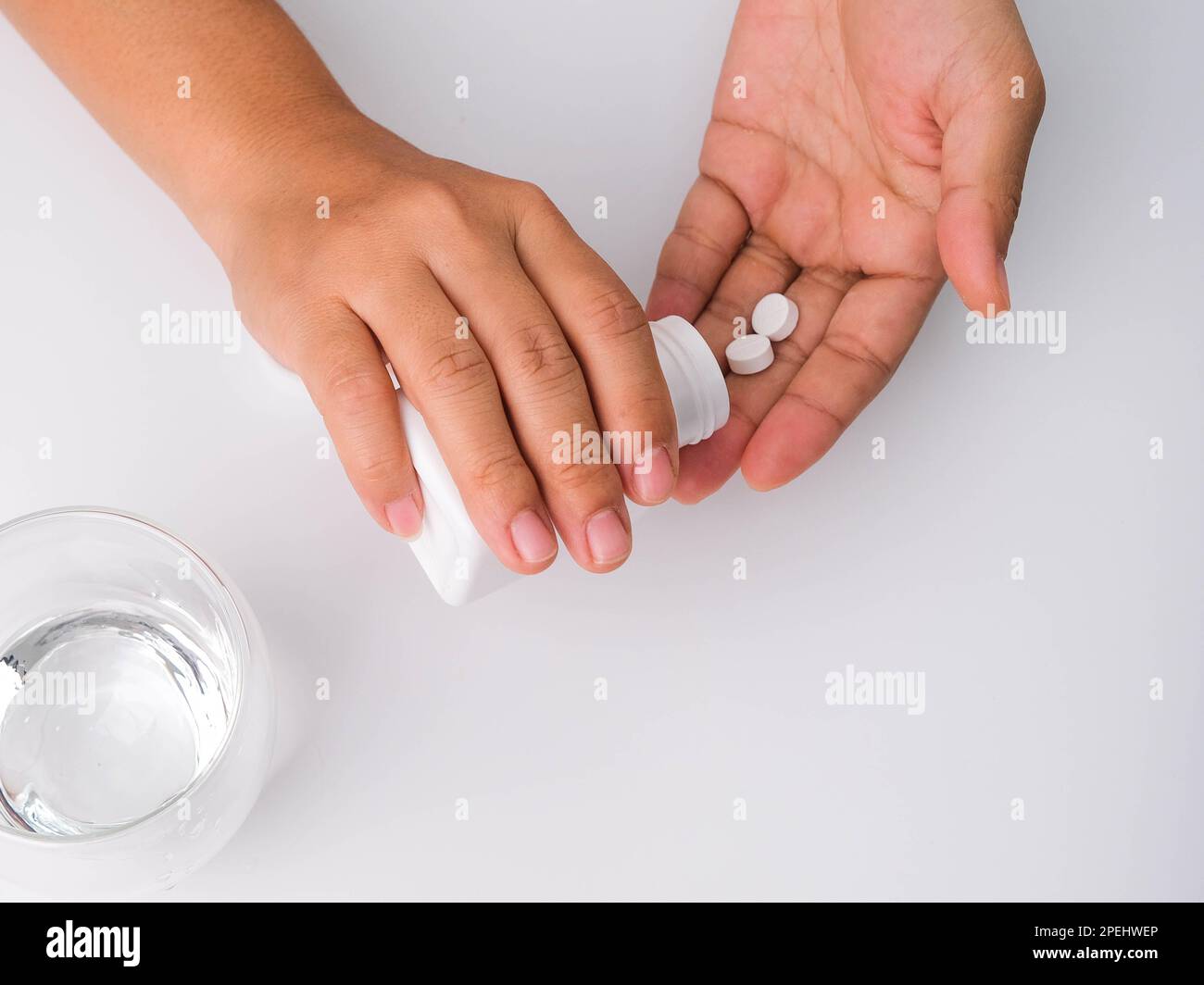 Close-up of woman pouring pills from bottle for medicinal purposes. Woman holding pills in hand with water. Healthcare, medicine, treatment, therapy c Stock Photo