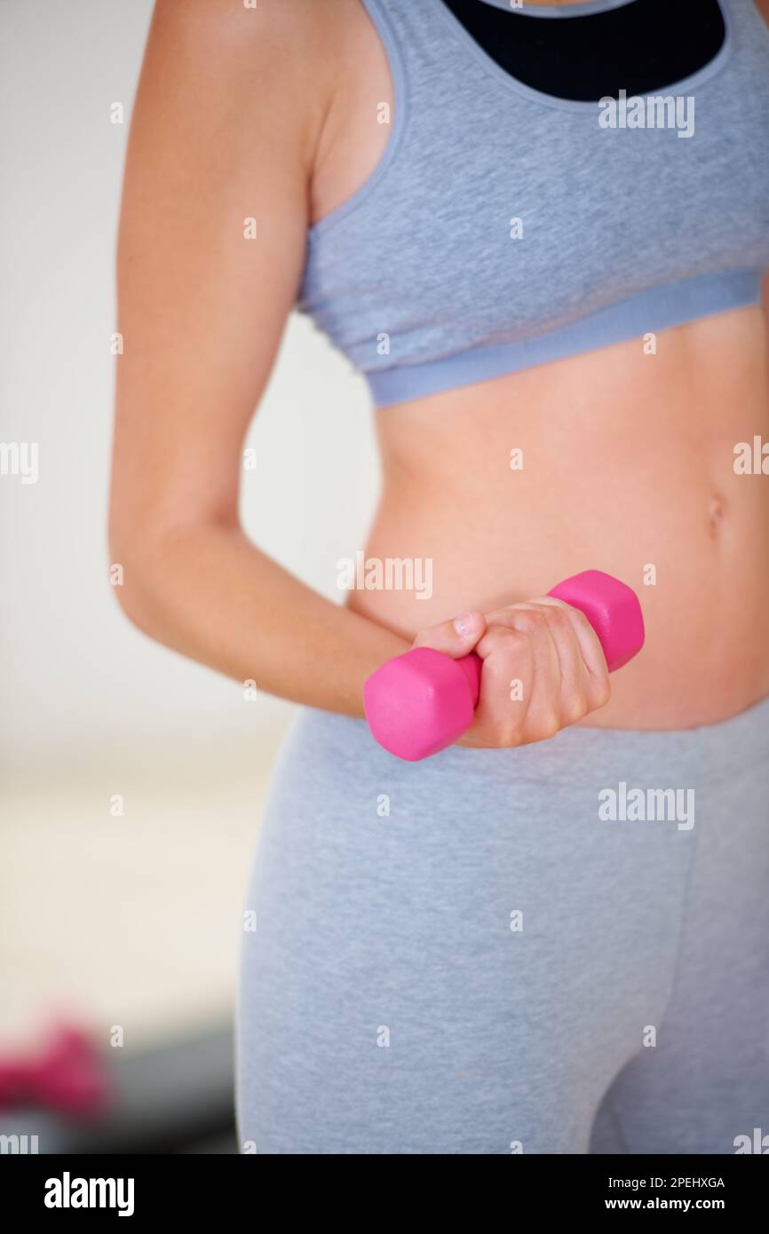 Toning her arms. Cropped image of a womans midriff while she is lifting a dumbbell at a gym. Stock Photo