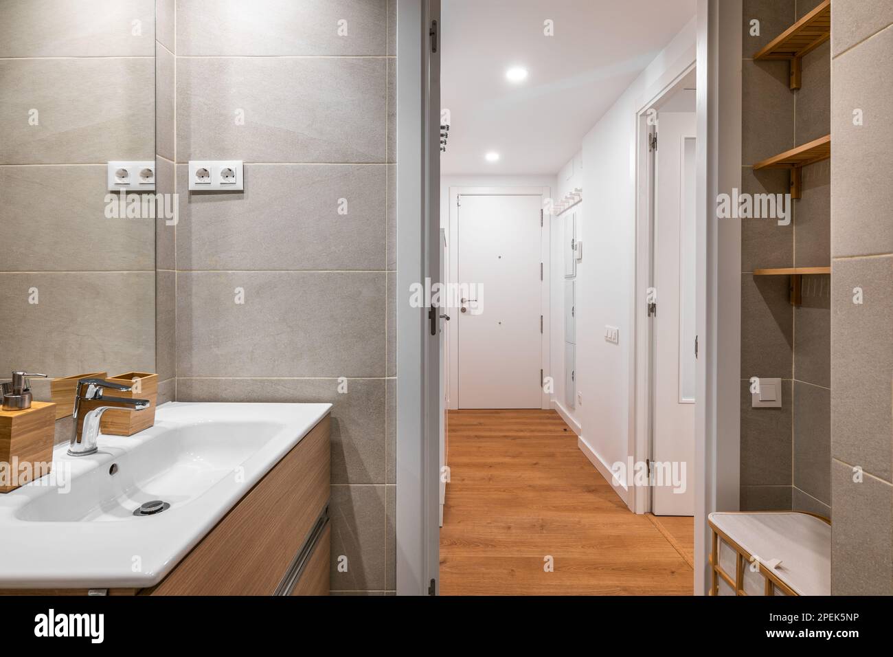 Open bathroom with sink and gray tile, mirror, overlooking the hall with closet in a minimalist but stylish apartment. The concept of concise design Stock Photo