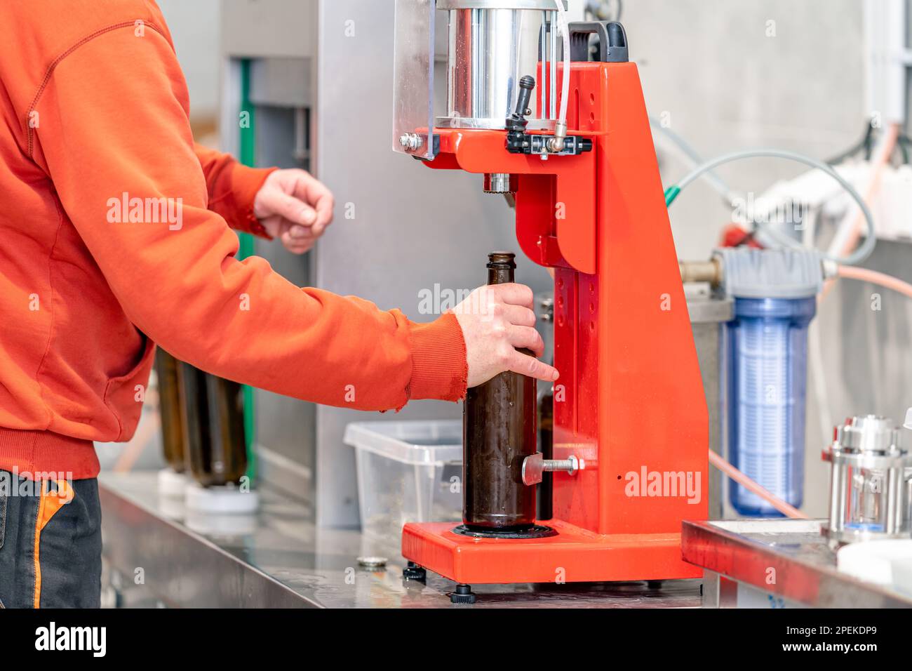 capping beer bottles on a machine in a brewery Stock Photo