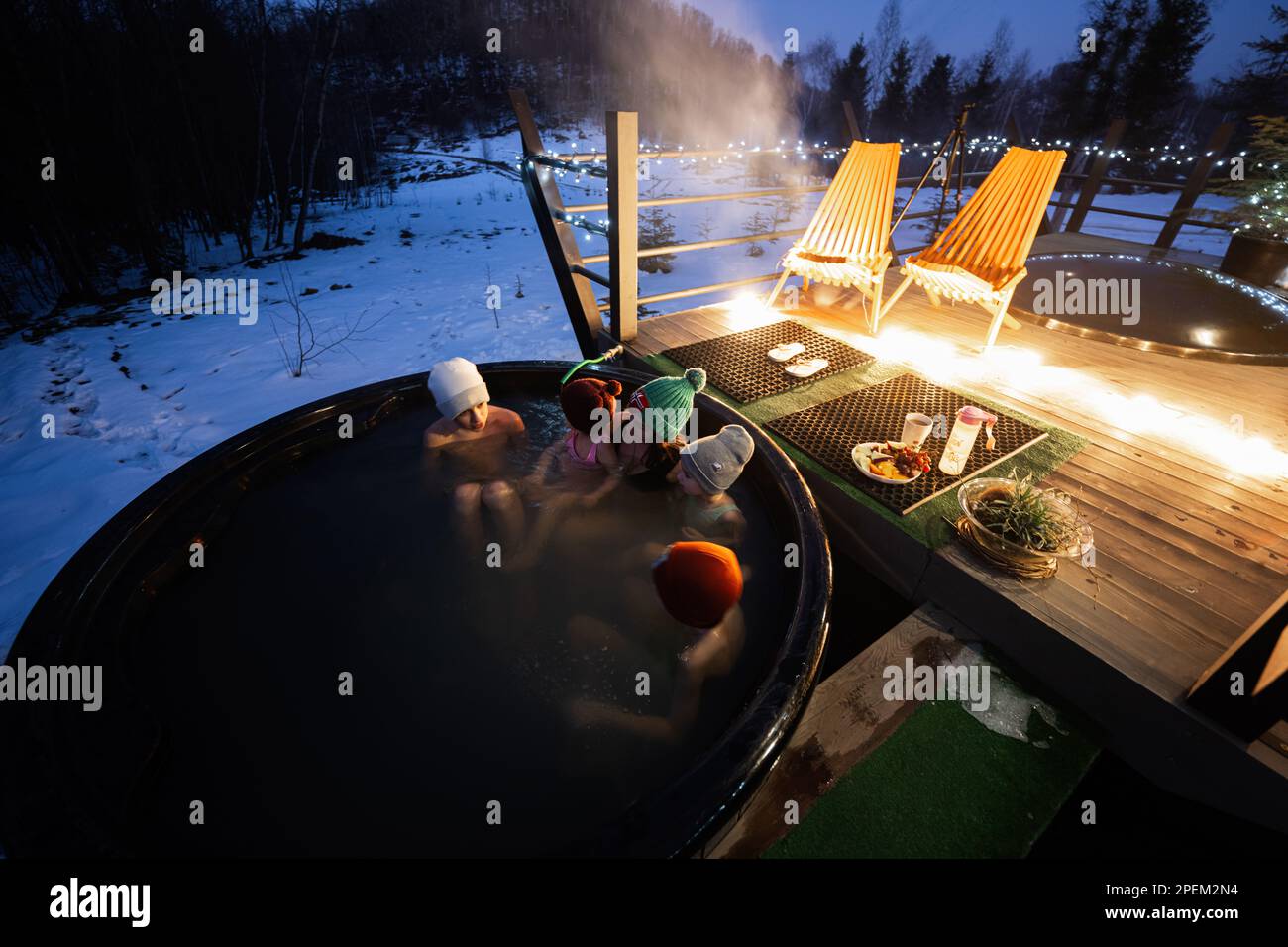 Family enjoying bathing in wooden barrel hot tub in the terrace of the
