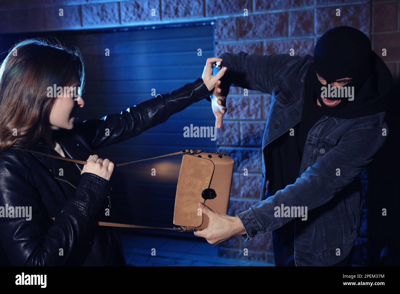 Woman using pepper spray while thief trying to steal her bag outdoors