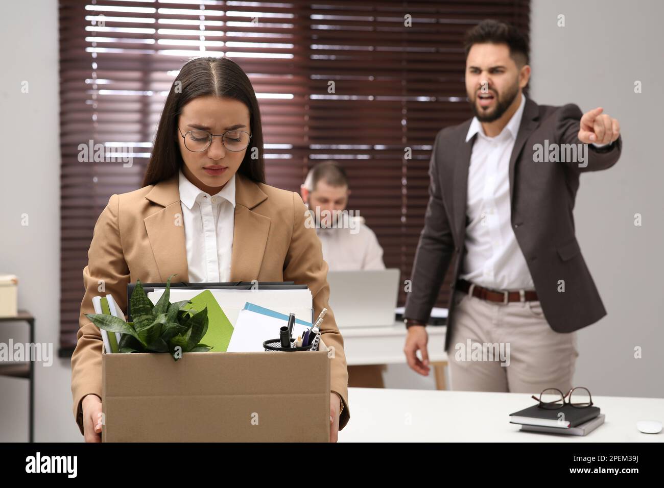 Boss dismissing young woman from work in office Stock Photo
