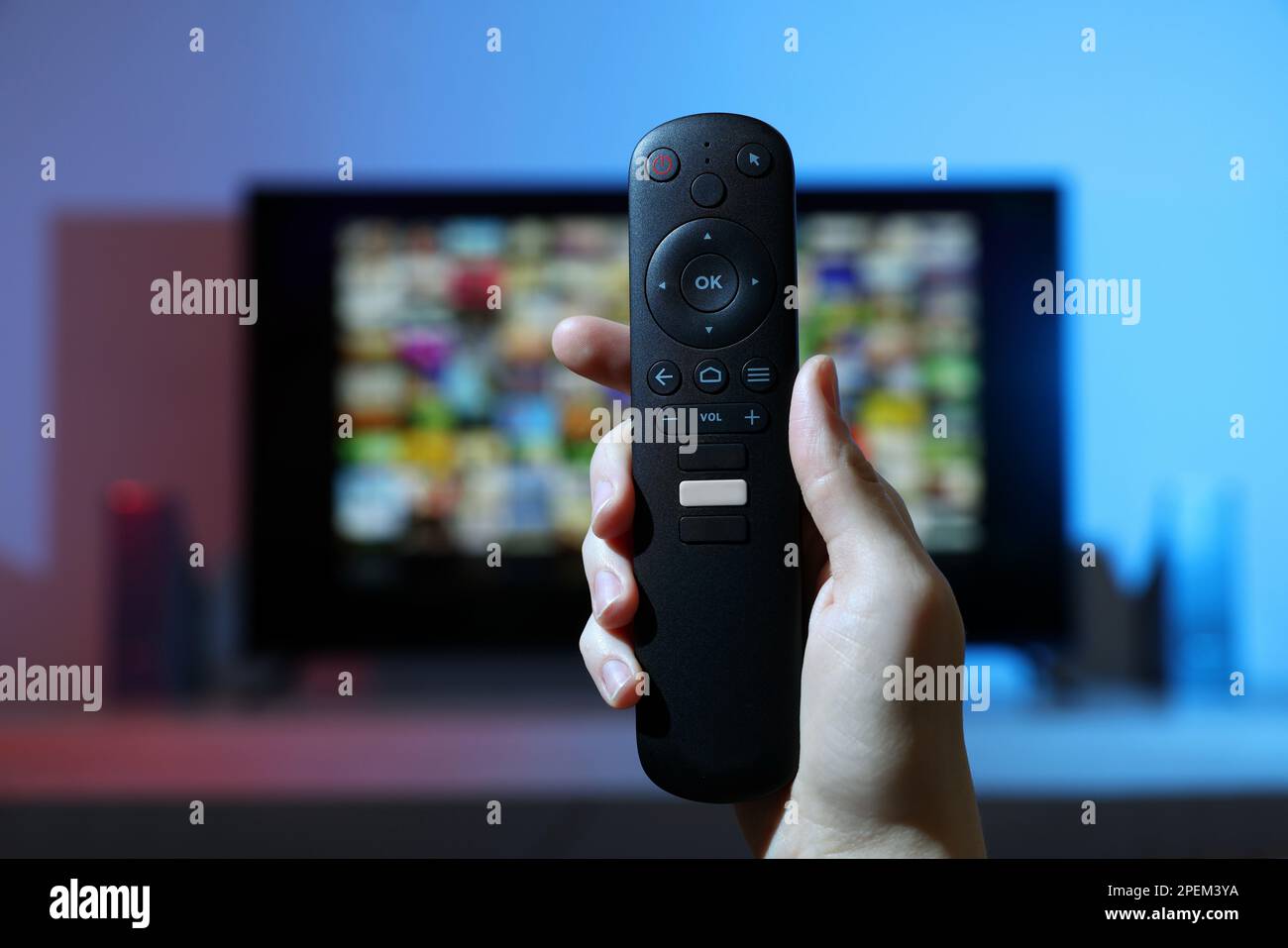 Woman switching channels on TV set with remote control at home, closeup ...