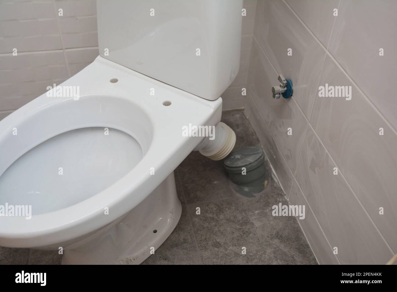 Close up on white toilet bowl installation and plumbing connecting