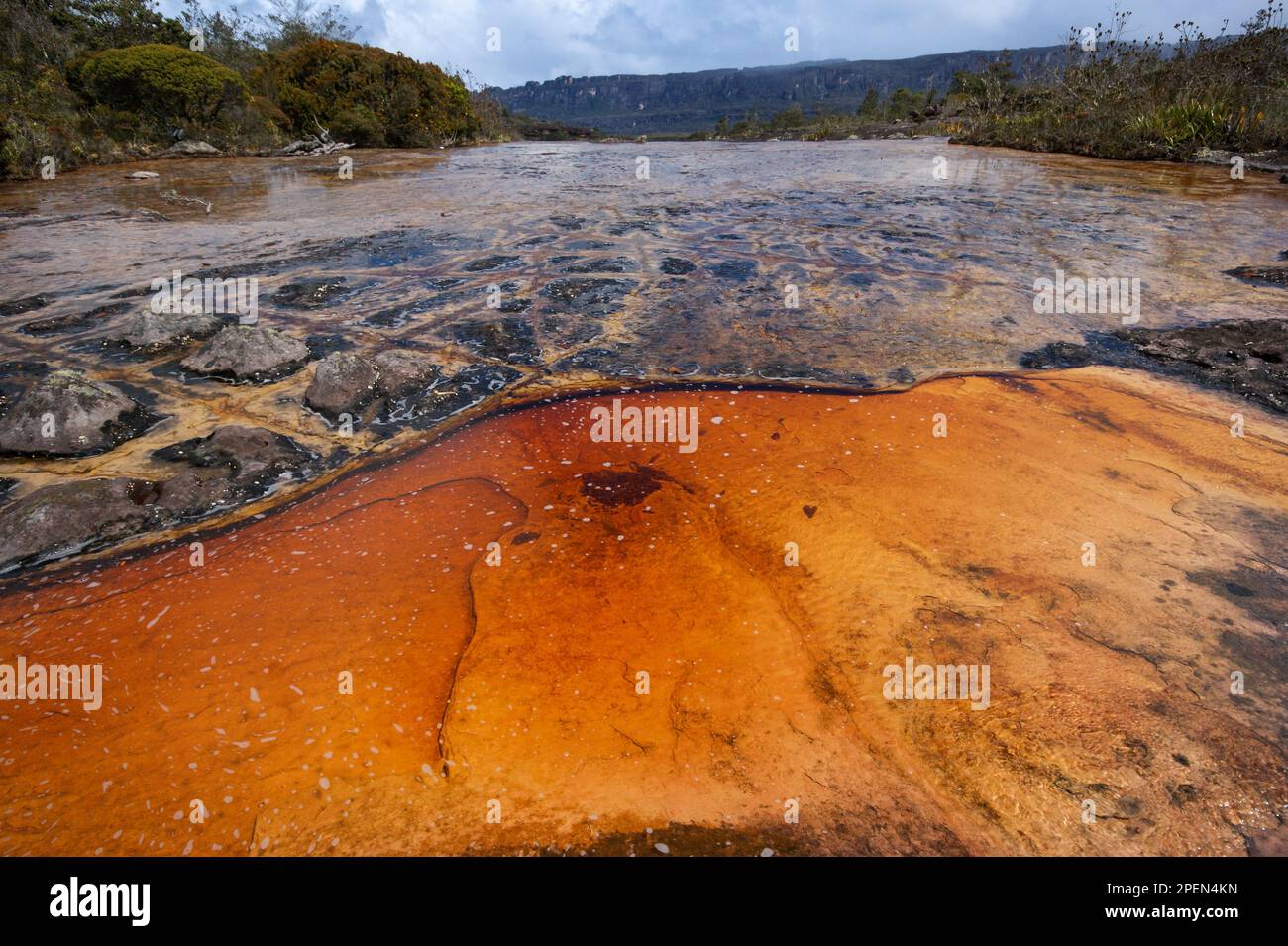 Orange and black rock structures in shallow river on the plateau of