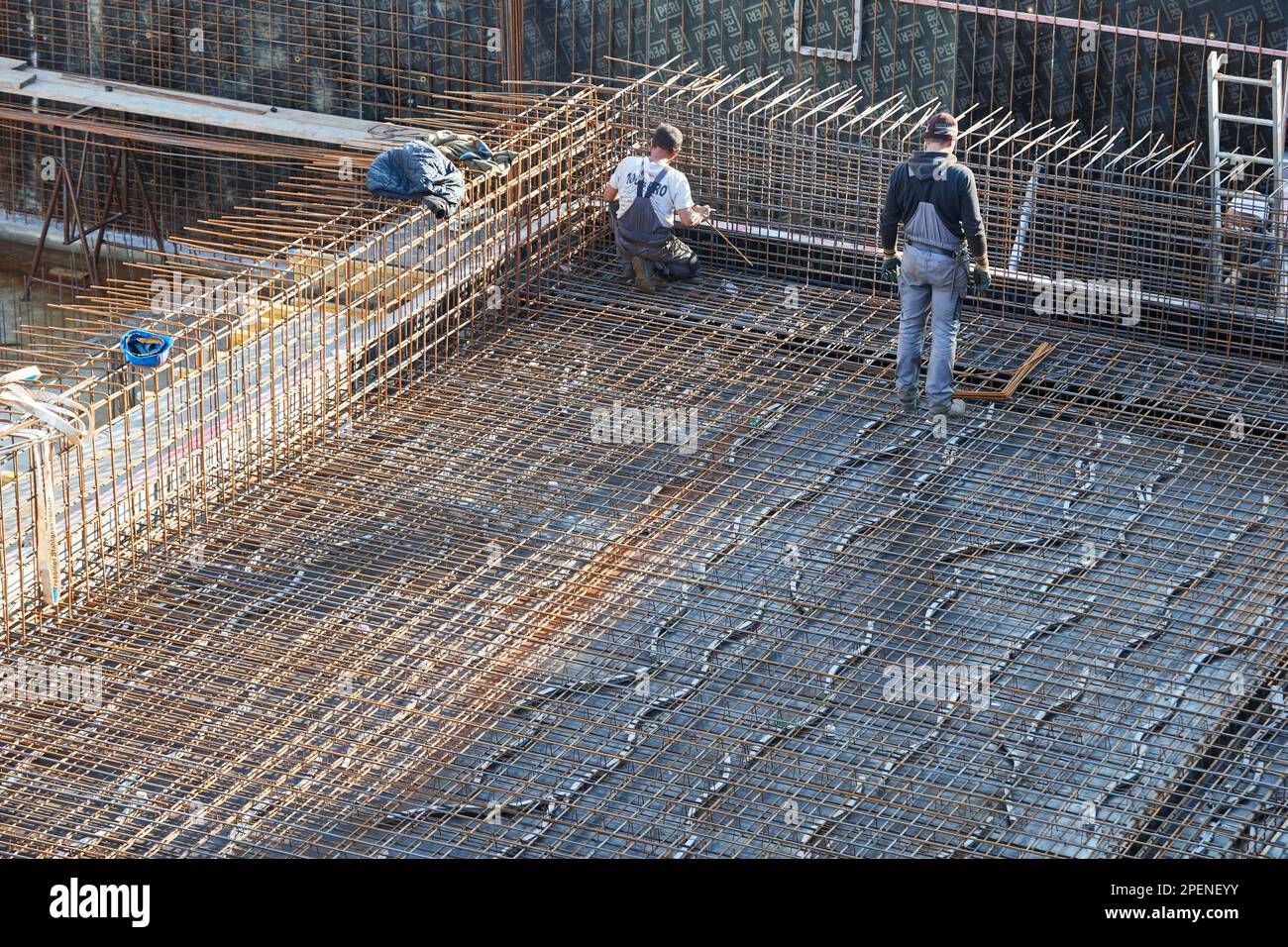 Worker connects steel reinforcement at concrete construction site Stock Photo