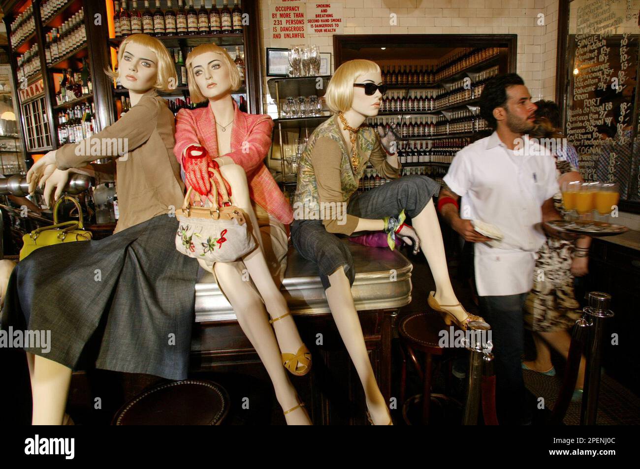 Mannequins propped up on a bar display clothes from the DKNY Spring