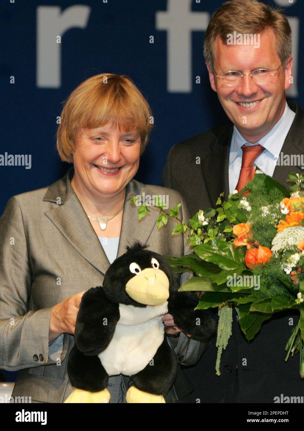 Die CDU Parteivorsitzende Angela Merkel, links, bekommt am Samstag, 28.  August 2004, beim Landesparteitag der niedersaechsischen Christdemokraten  in Hannover einen Stoff-Pinguin geschenkt. Die Politikerin ist Patin des  Pinguins "Helmut" im Zoo von