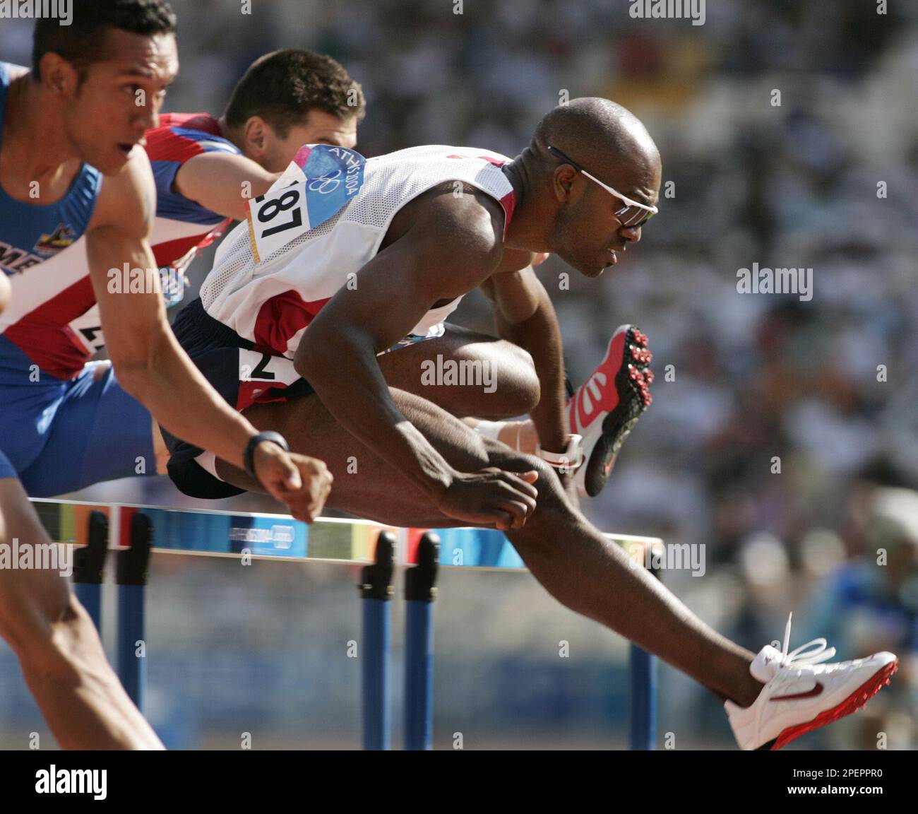 Allen Johnson, of the United States, right, clears a hurdle in a ...