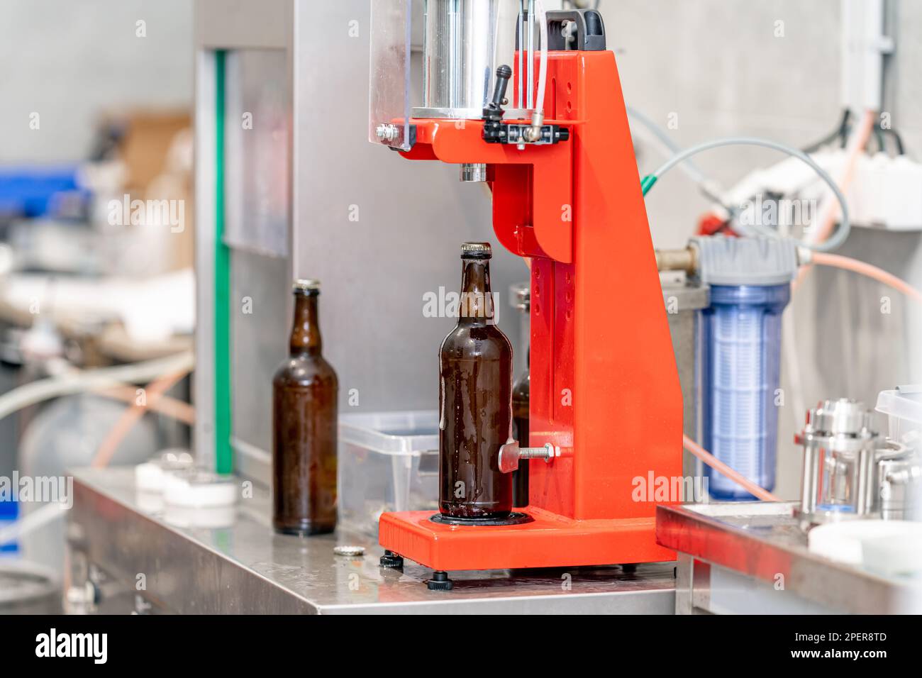 capping beer bottles on a machine in a brewery Stock Photo