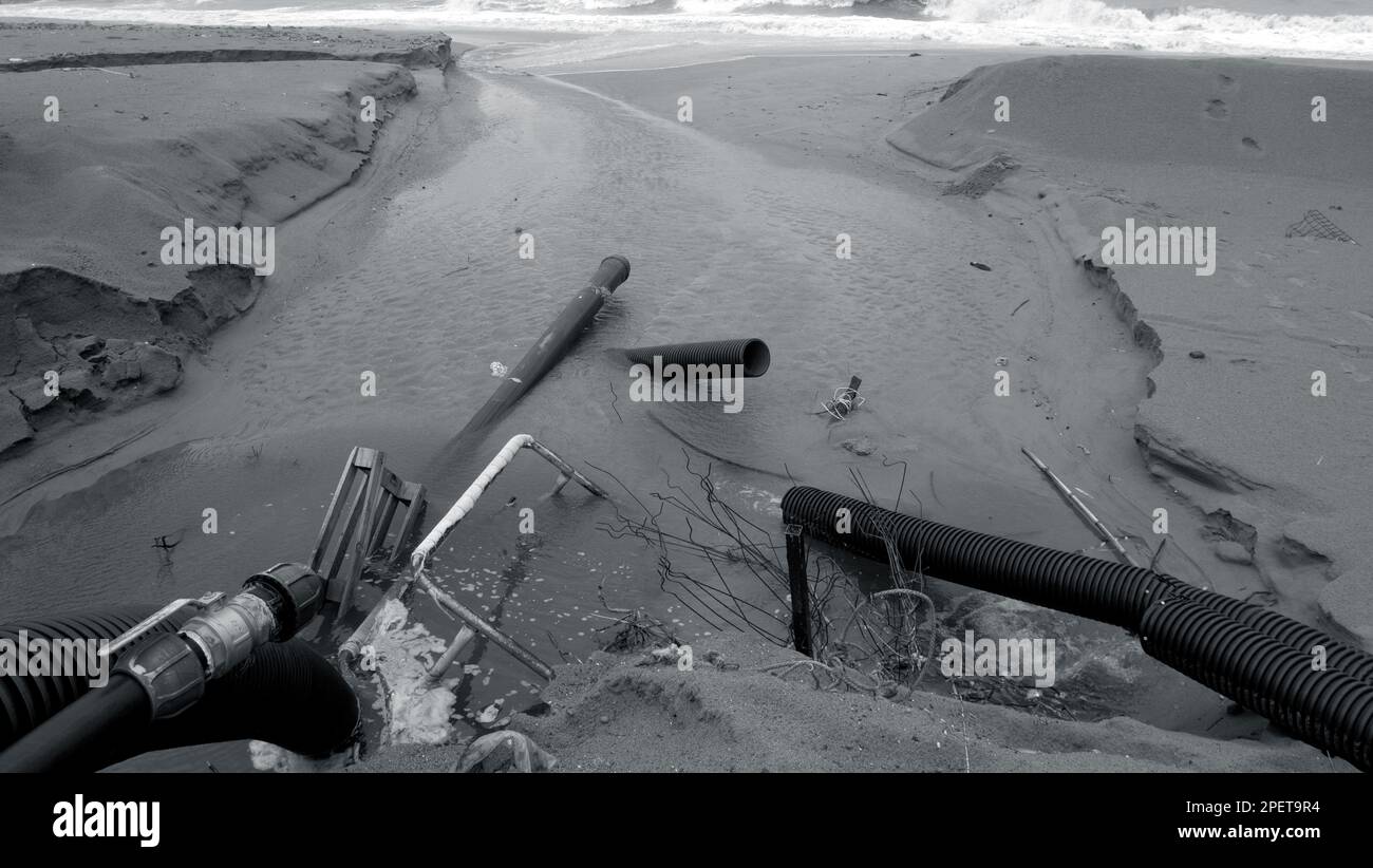 Industrial wastewater, the pipeline discharges liquid industrial waste into the sea on a city beach. Dirty sewage flows from a plastic sewer pipe onto Stock Photo
