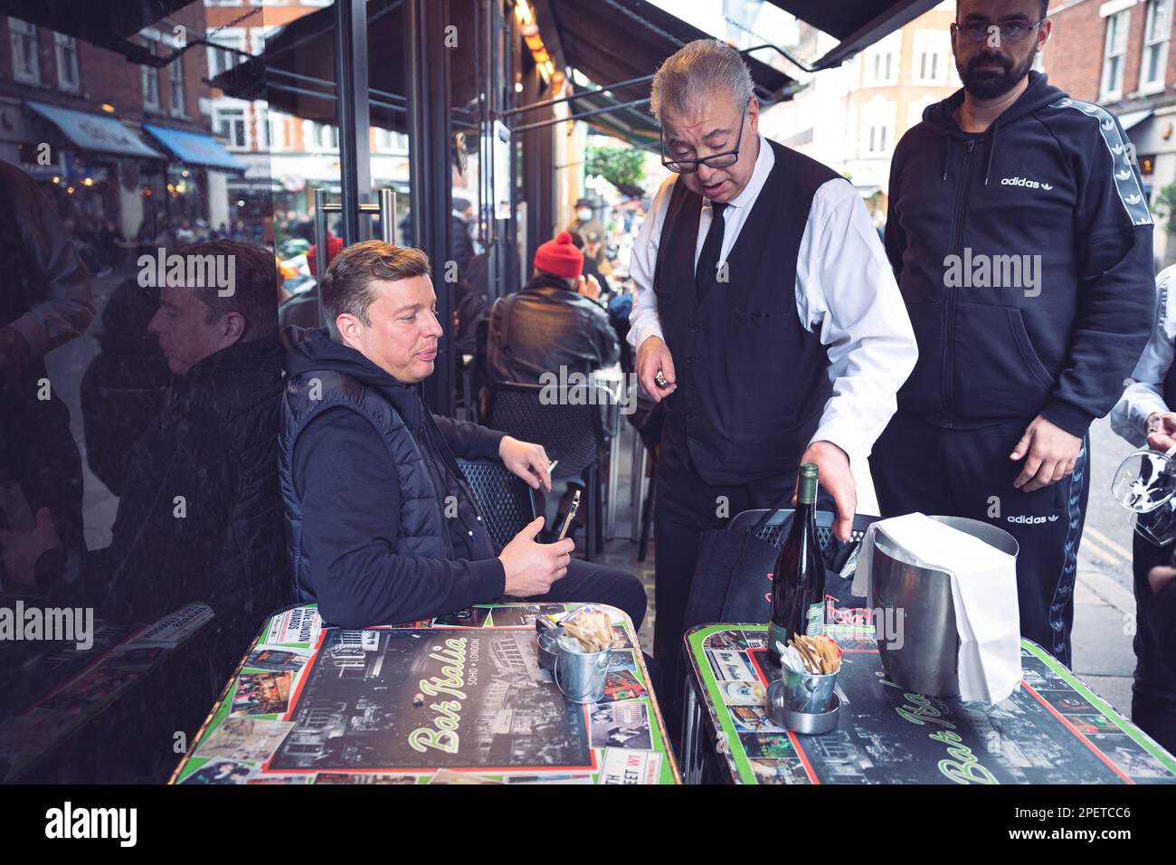 Thomas Henry Skinner, the English businessman and television personality watches the waiter pouring white wine in Soho, London, 02 2023 Stock Photo