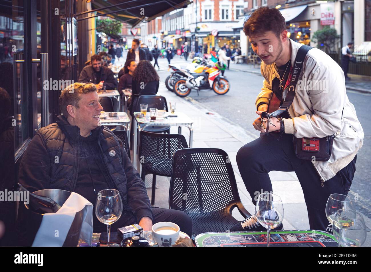 Thomas Henry Skinner the English businessman and television personality enjoys the young ukelele rapper in Soho, Liam C, cloudy winter London 2023 Stock Photo