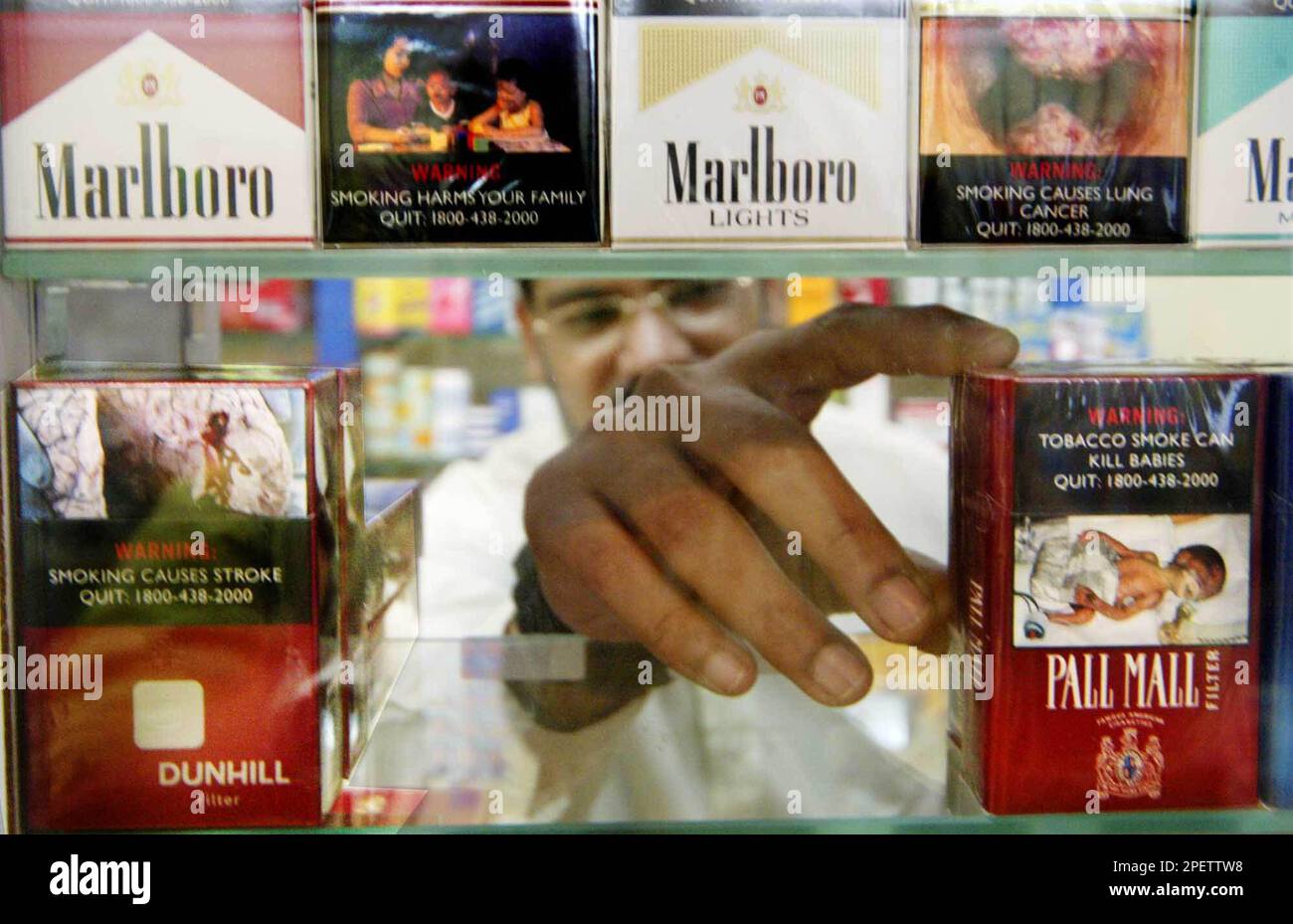 A Singaporean shopkeeper reaches to get a pack of cigarettes illustrated  with photographs depicting the potential consequences of smoking Monday  July 19, 2004 in Singapore. Singapore's government has mandated that all  cigarette