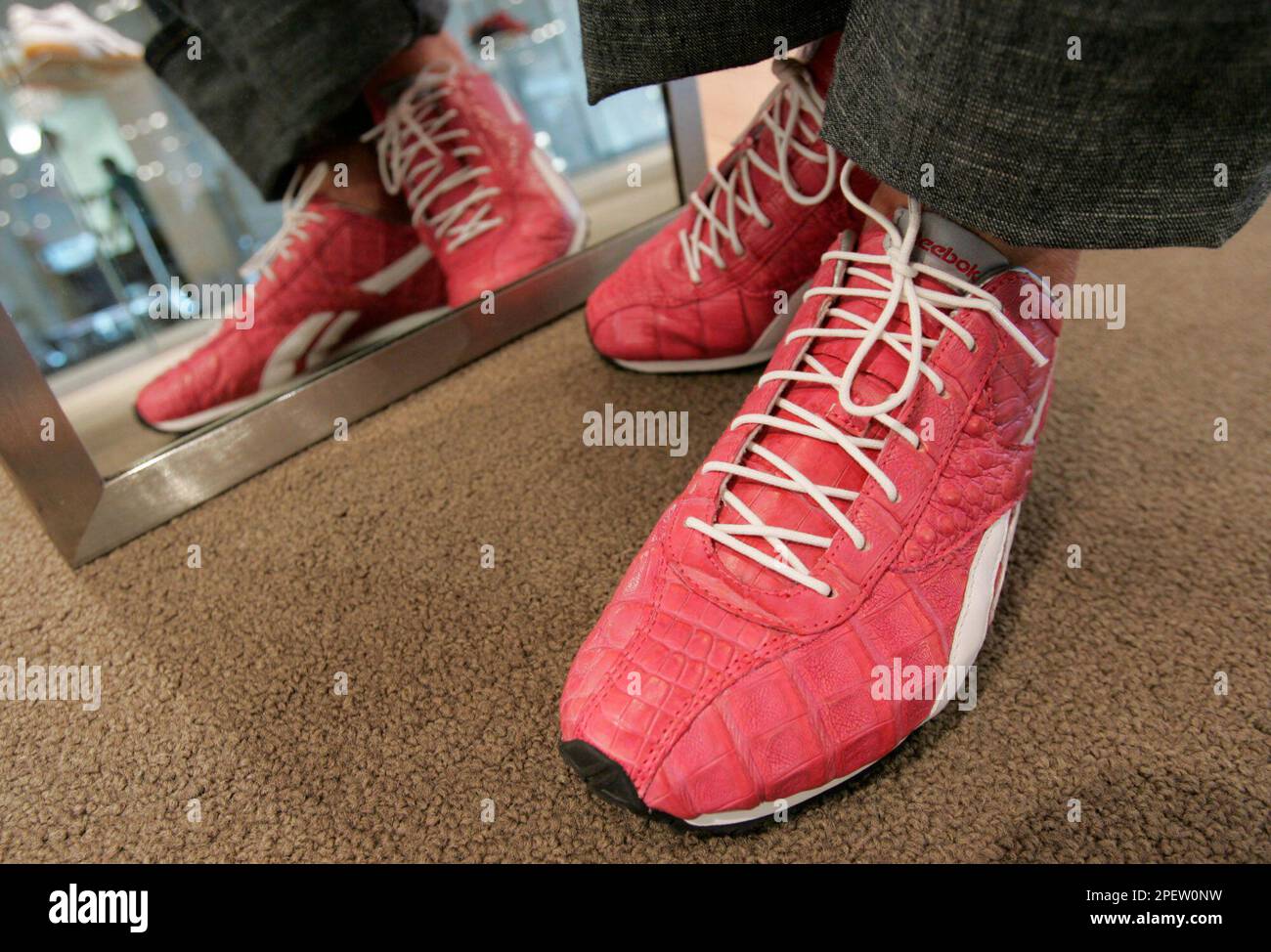 Model Kelly Donovan displays a pair of pink crocodile skin Reebok sneakers  at Reebok headquarters, in Canton, Mass., Wednesday, July 14, 2004. The  limited edition shoes, which retail for $1,050, are available