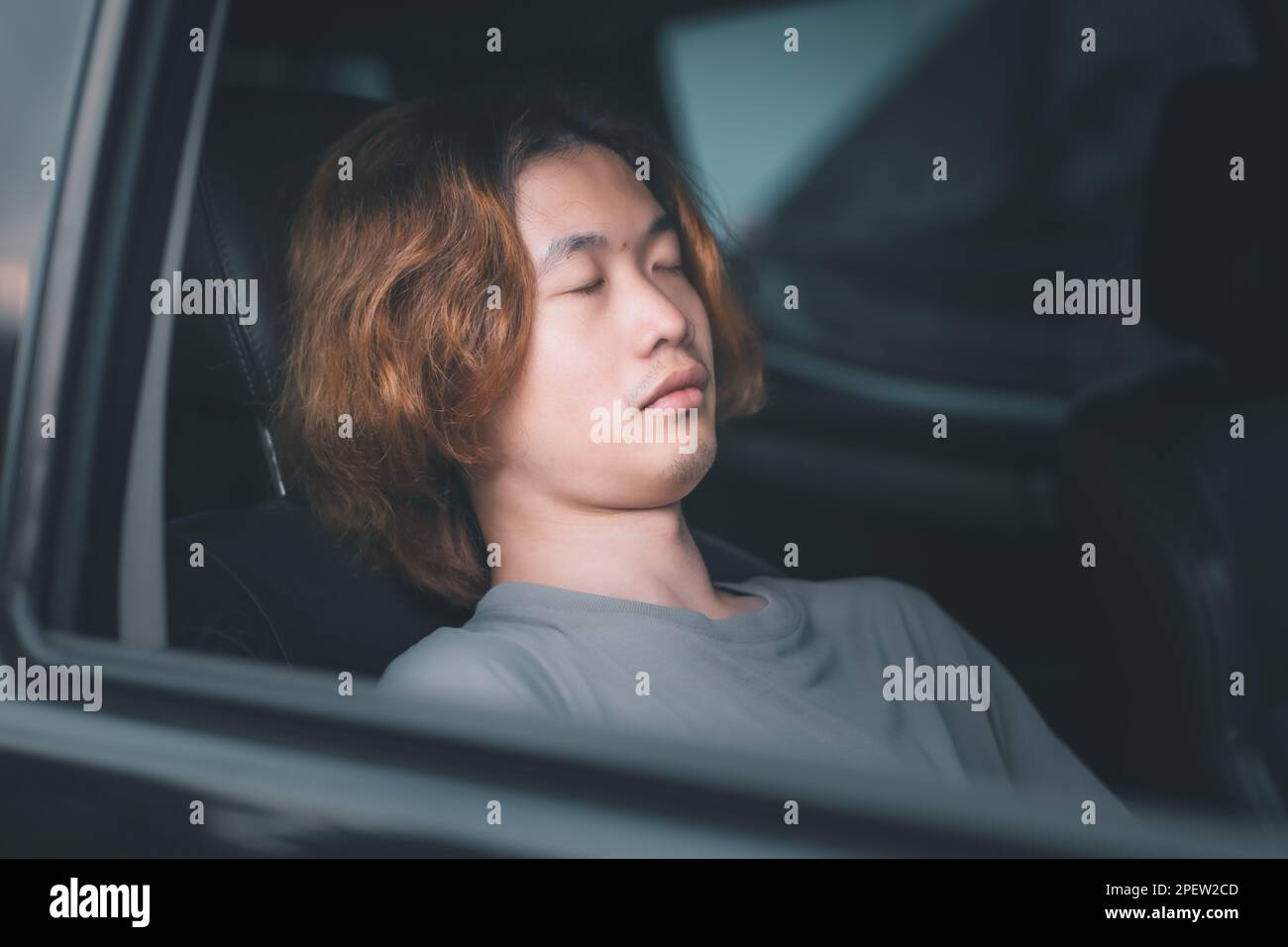 Young asian man with long hair sleeping in his car Stock Photo - Alamy