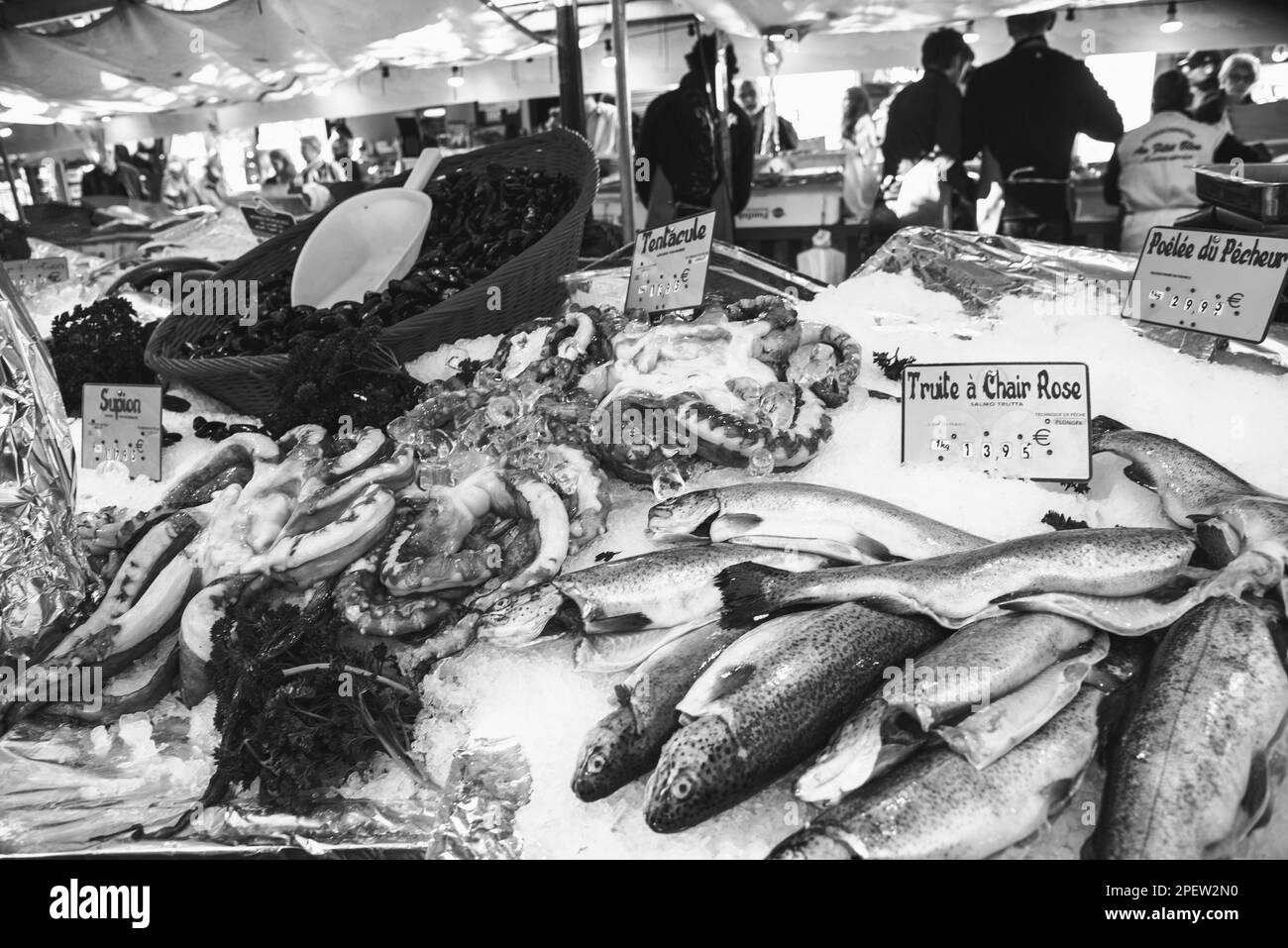 Fresh seafood and fish for sale at street market at Parisian suburb. Blurry silhouettes of