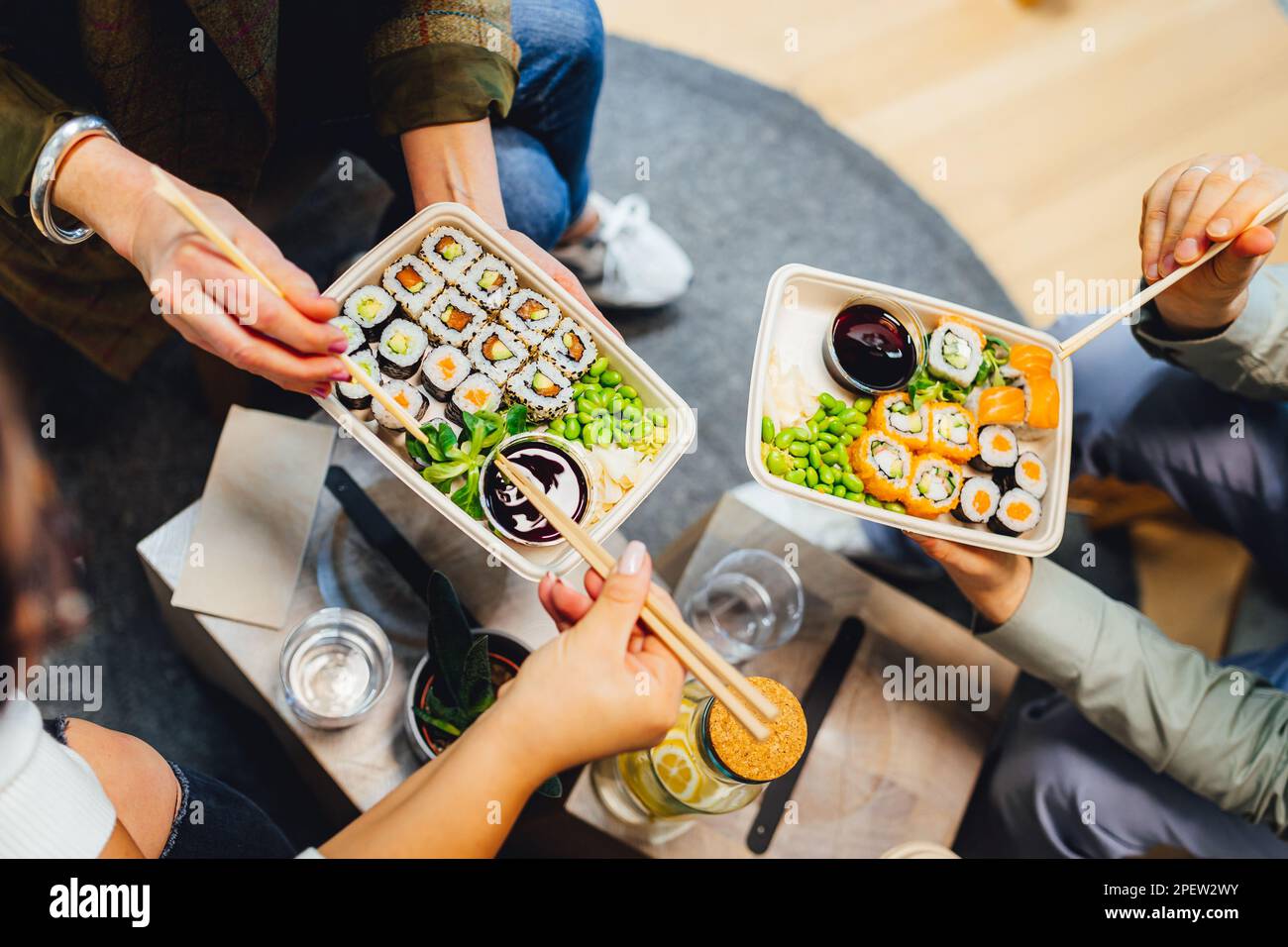 Three people enjoying sushi together while seated around a table Stock Photo