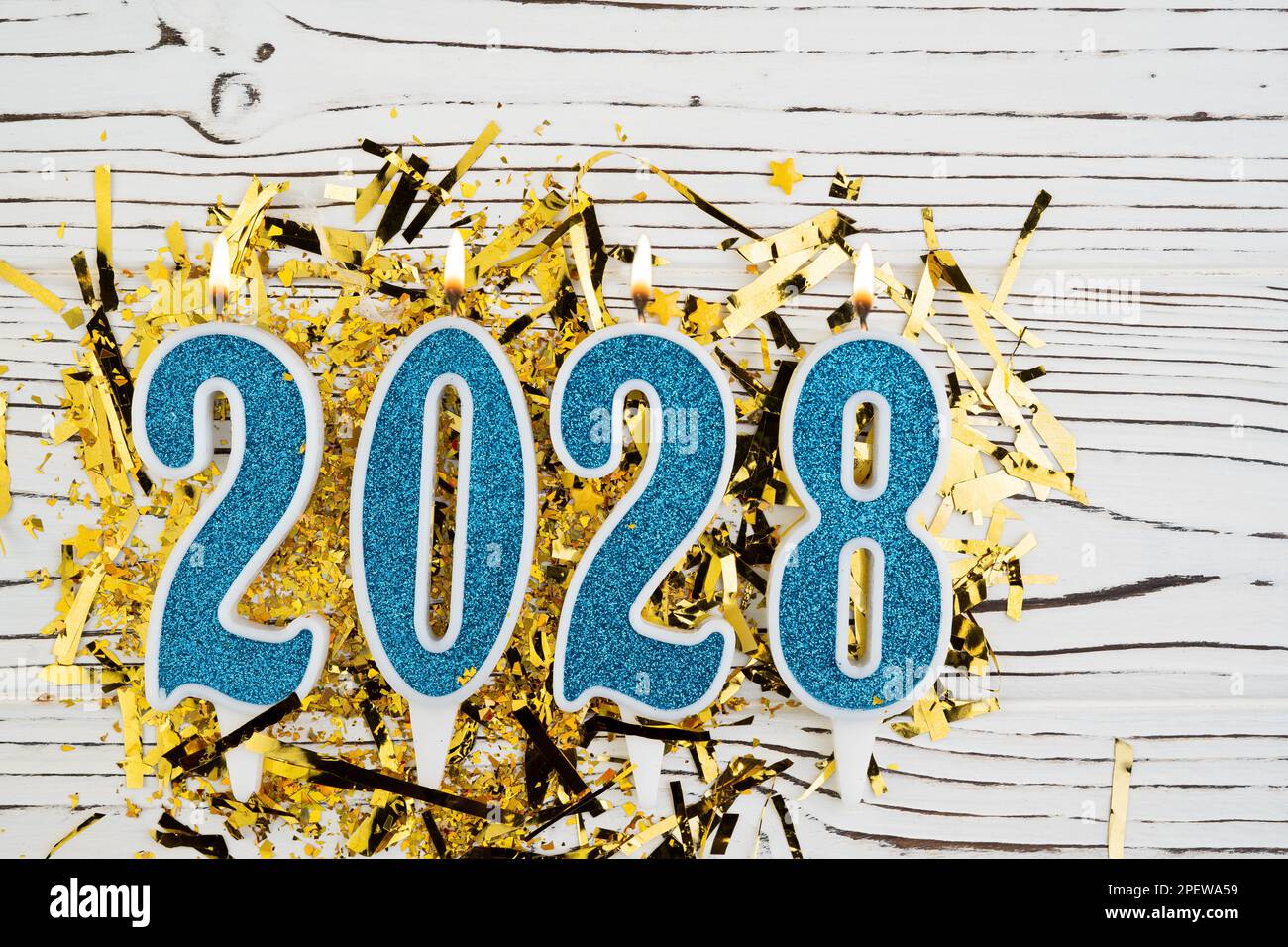 Holiday background Happy New Year 2028. Numbers of year 2028 made by blue candles on festive white wooden background. Celebrating New Year holiday Stock Photo