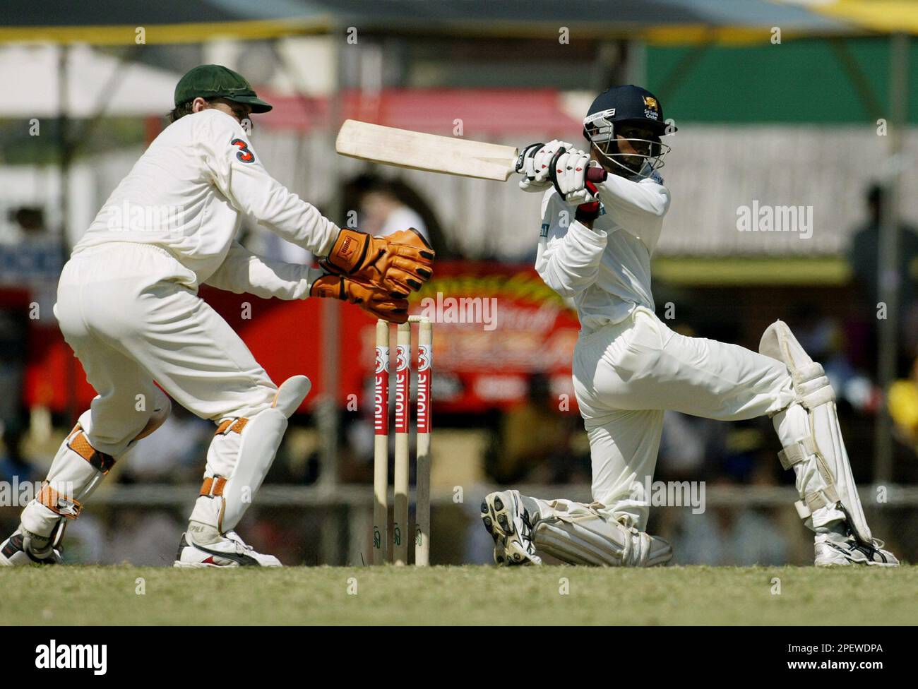 Sri Lanka s batsman Russell Arnold right plays a pull shot as Australia s wicket keeper Adam Gilchrist left looks on during play on day three of the first cricket test in Darwin Australia