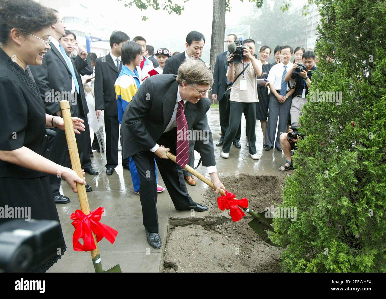 Microsoft founder Bill Gates, center, plants a tree with school principal  Yuan Aijun, left, during a visit to a middle school in Beijing Thursday  July 1, 2004. Gates donated computers and software