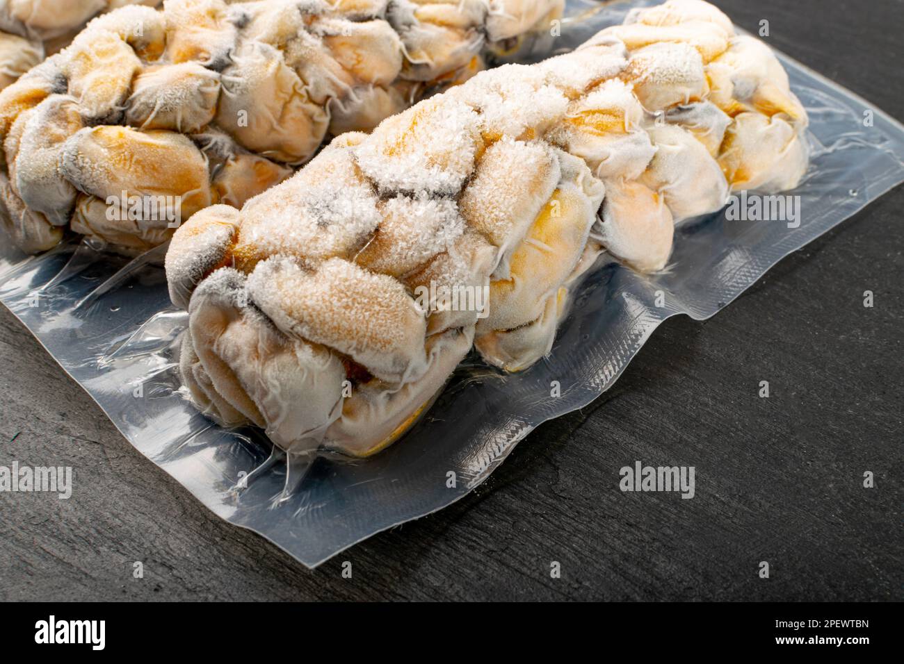 Packed Frozen Mussels, Unshelled Clam, Frozen Peeled Mussel, Cold Mussels Meat, Iced Seafood, Cooked Shellfish on Black Stone Background Closeup Stock Photo