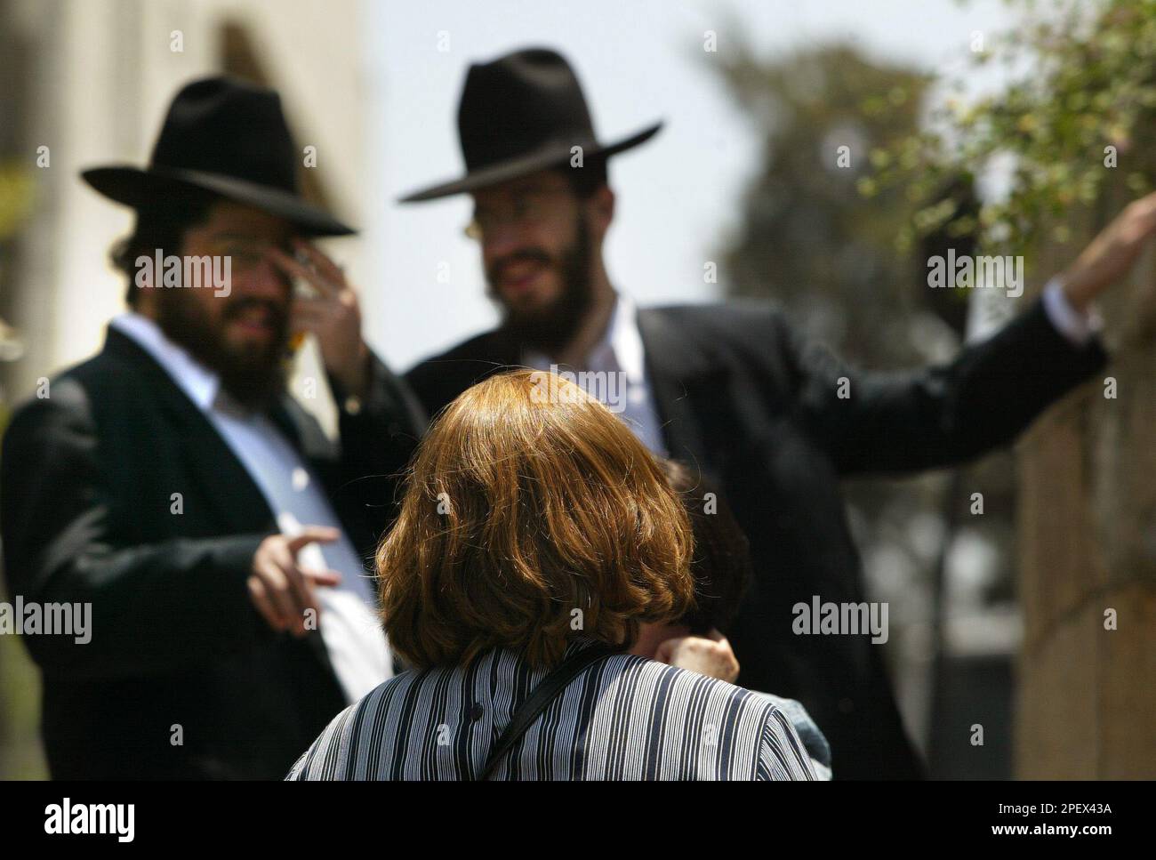 Ultra Orthodox Jewish men look on as an Orthodox Jewish woman wearing a wig  passes by, in the traditional neighborhood of Mea Shearim, in Jerusalem,  Tuesday, June 22, 2004. Recently, a senior