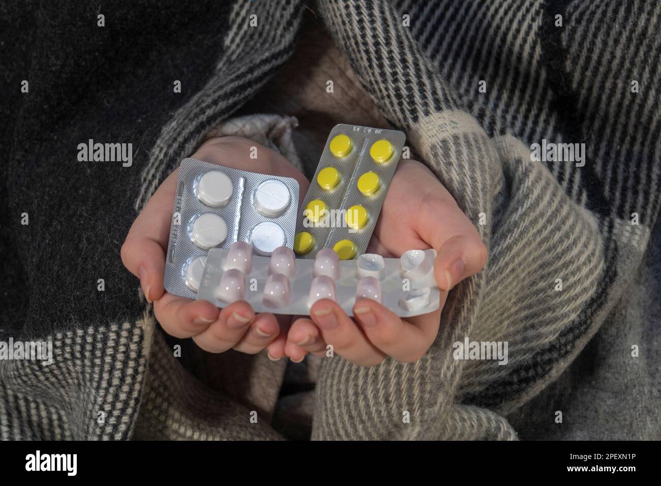 A woman in a plaid holds blisters of pills in her hands (close-up). The concept of medicine, pharmacy, healthcare and treatment at home Stock Photo